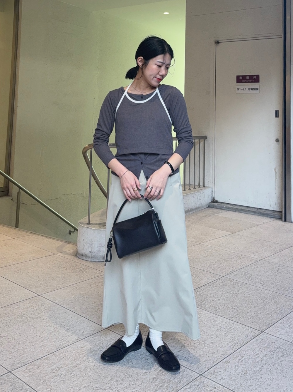 グレー系のTシャツ/カットソー、ブラック系のローファー、ベージュ系のスカートを着用したレディースの冬コーディネートの1枚目の写真