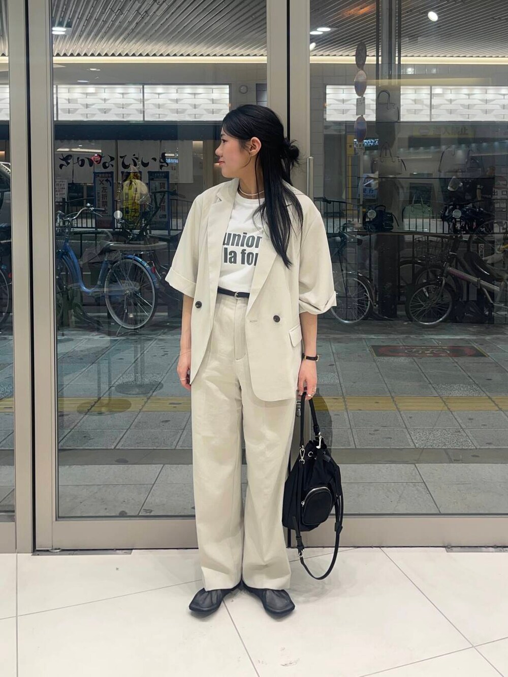 ブラック系のショルダーバッグ、ブラック系のパンプス、ホワイト系のTシャツ/カットソーを着用したレディースの春コーディネートの1枚目の写真