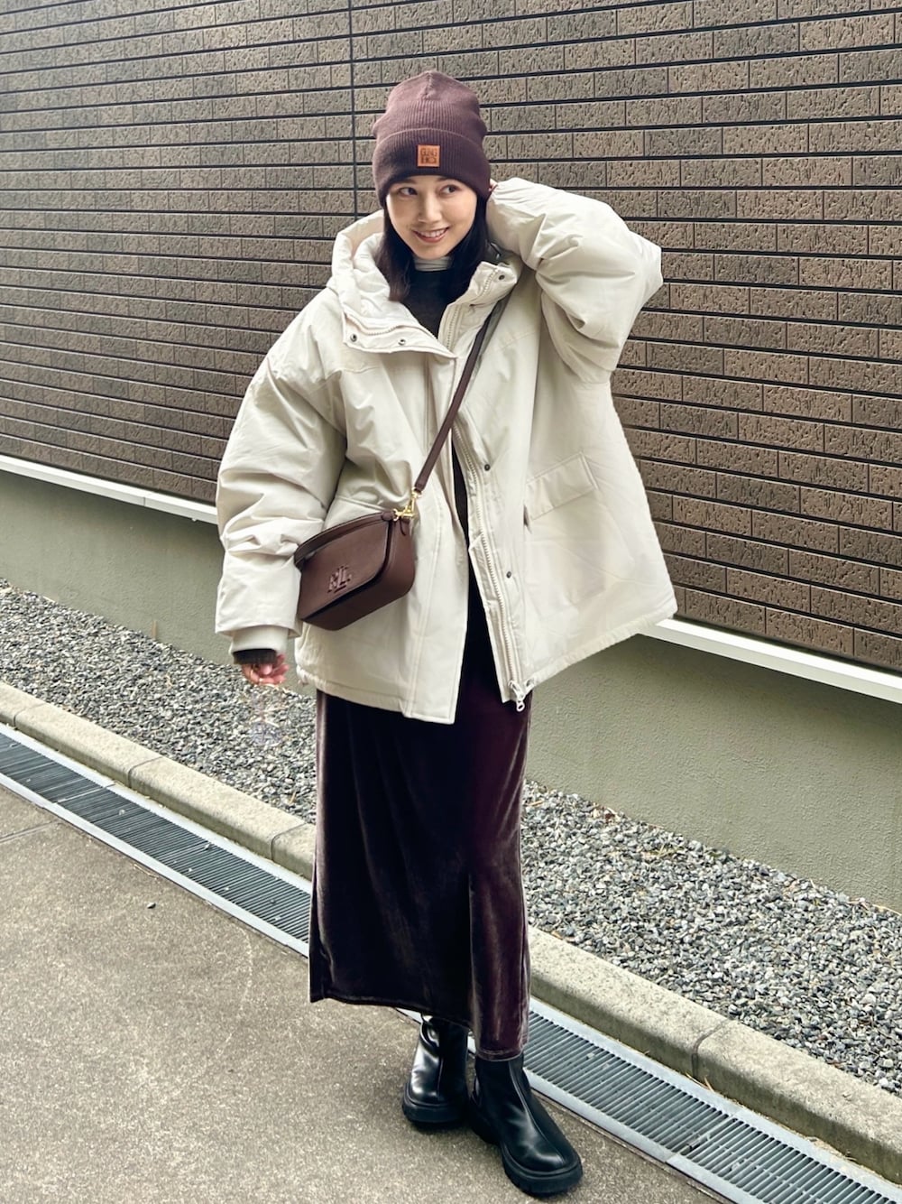 ホワイト系のブルゾン、ブラック系のブーツ、ブラウン系のニット/セーターを着用したレディースの冬コーディネートの1枚目の写真
