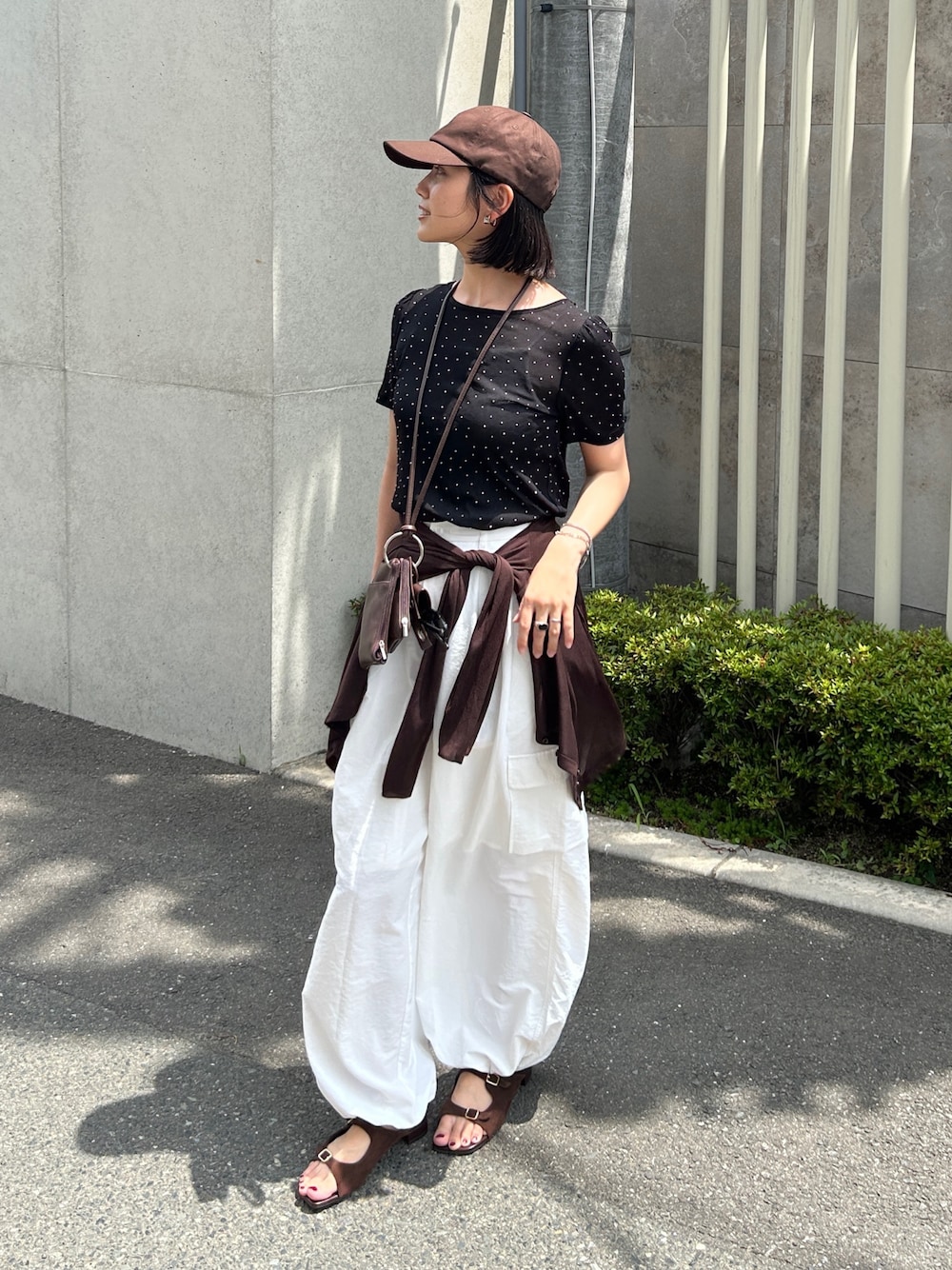 ホワイト系のカーゴパンツ、ブラック系のTシャツ/カットソー、ブラウン系のショルダーバッグを着用したレディースの夏コーディネートの1枚目の写真