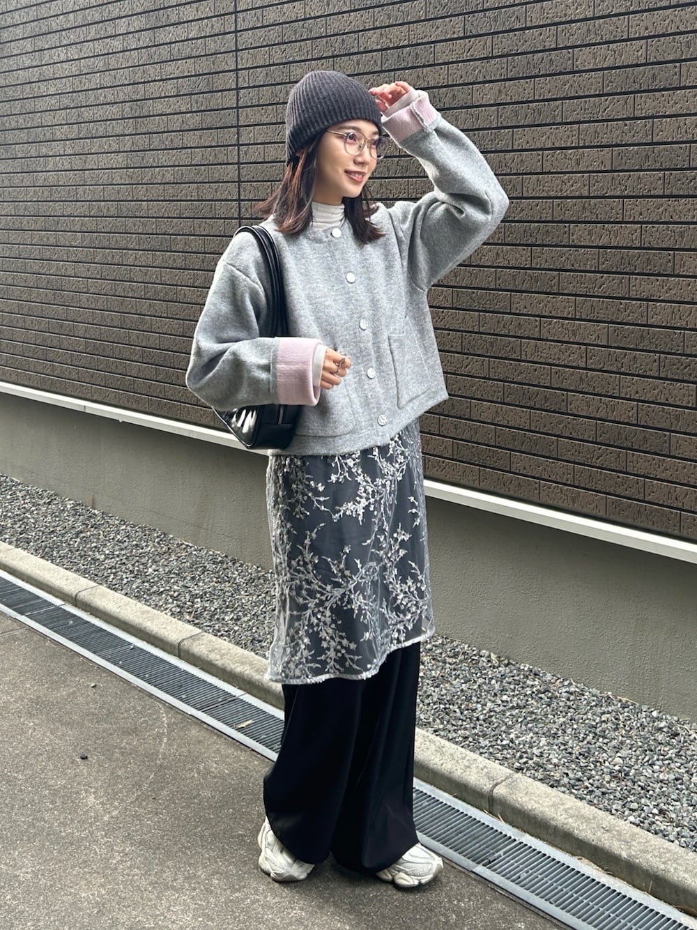 グレー系のカーディガン/ボレロ、シルバー系のワンピース、ブラック系のスラックスを着用したレディースの冬コーディネートの1枚目の写真