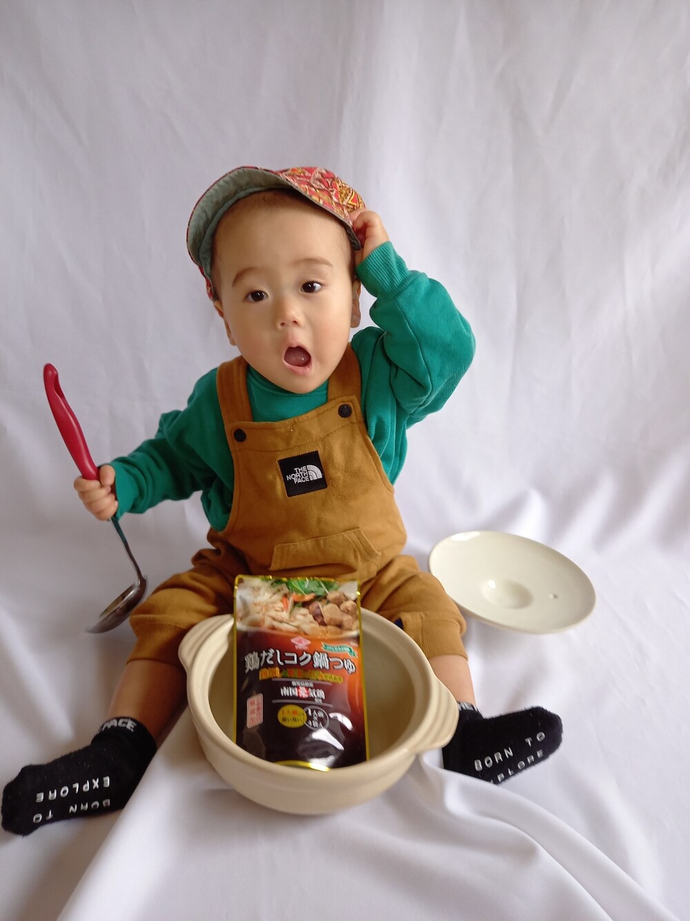 グリーン系のスウェット、ブラウン系のオールインワン・サロペット、レッド系のキャップを着用したキッズの冬コーディネートの3枚目の写真