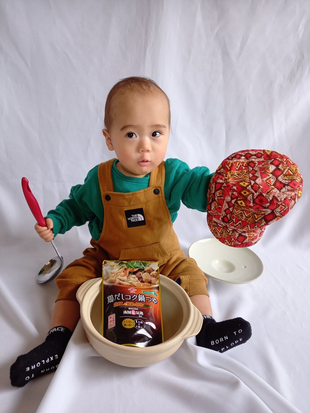 グリーン系のスウェット、ブラウン系のオールインワン・サロペット、レッド系のキャップを着用したキッズの冬コーディネートの2枚目の写真