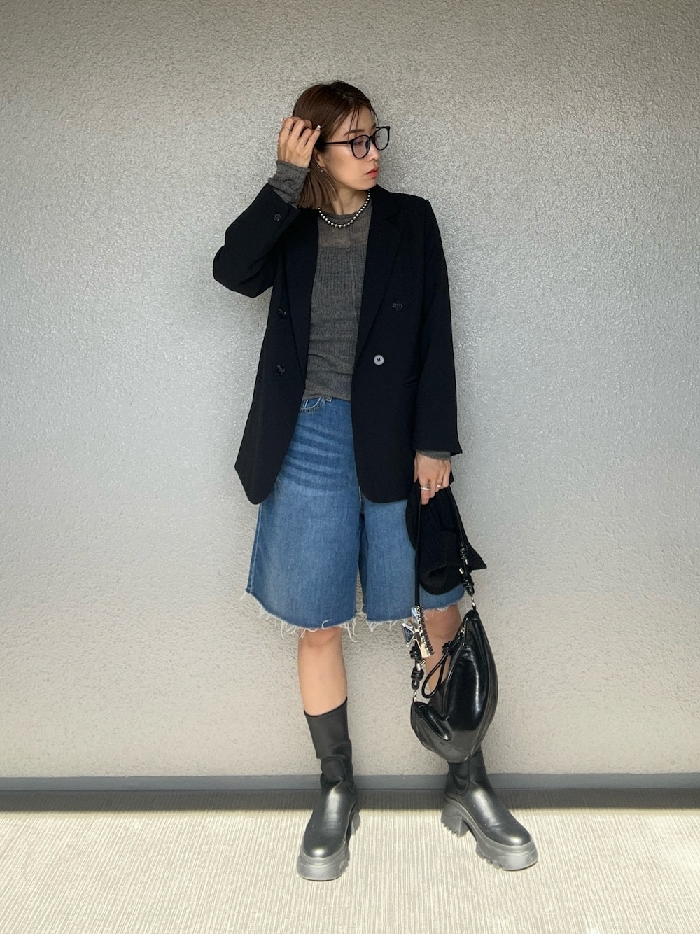 ブラック系のハンドバッグ、グレー系のニット/セーター、ブラック系のテーラードジャケットを着用したレディースの秋コーディネートの1枚目の写真