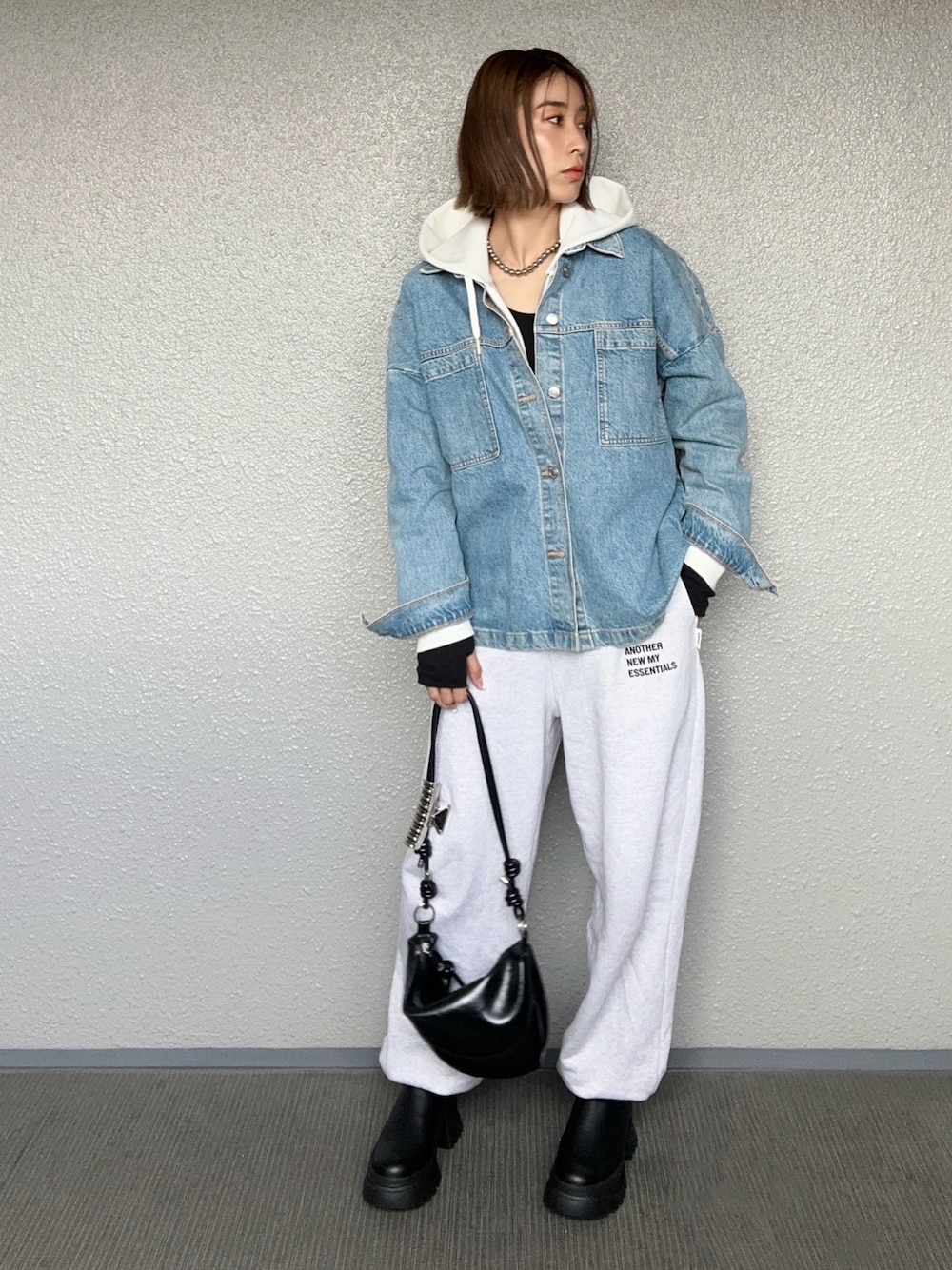 ブラック系のブーツ、ブラック系のハンドバッグ、ベージュ系のスウェットパンツを着用したレディースの秋コーディネートの1枚目の写真