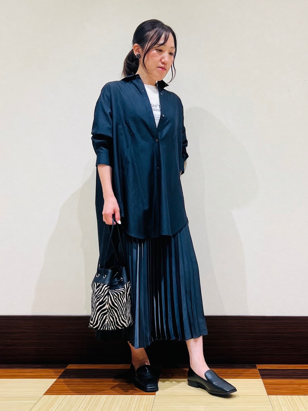 ブラック系のシャツ/ブラウス、ホワイト系のTシャツ/カットソー、グレー系のスカートを着用したレディースの秋コーディネートの1枚目の写真