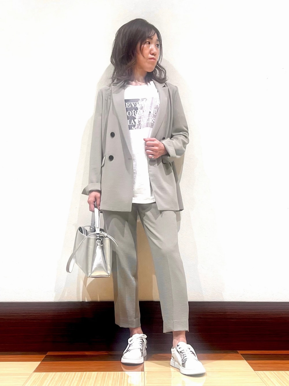 ベージュ系のスーツジャケット、ホワイト系のTシャツ/カットソー、ベージュ系のスーツパンツを着用したレディースの春コーディネートの1枚目の写真