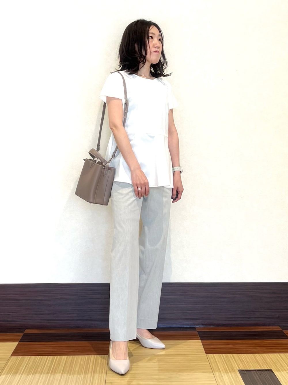 ホワイト系のシャツ/ブラウス、グレー系のスーツパンツ、ベージュ系のショルダーバッグを着用したレディースの夏コーディネートの1枚目の写真