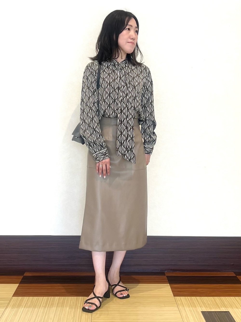 ブラウン系のシャツ/ブラウス、ベージュ系のスカート、ブラック系のサンダルを着用したレディースの秋コーディネートの1枚目の写真