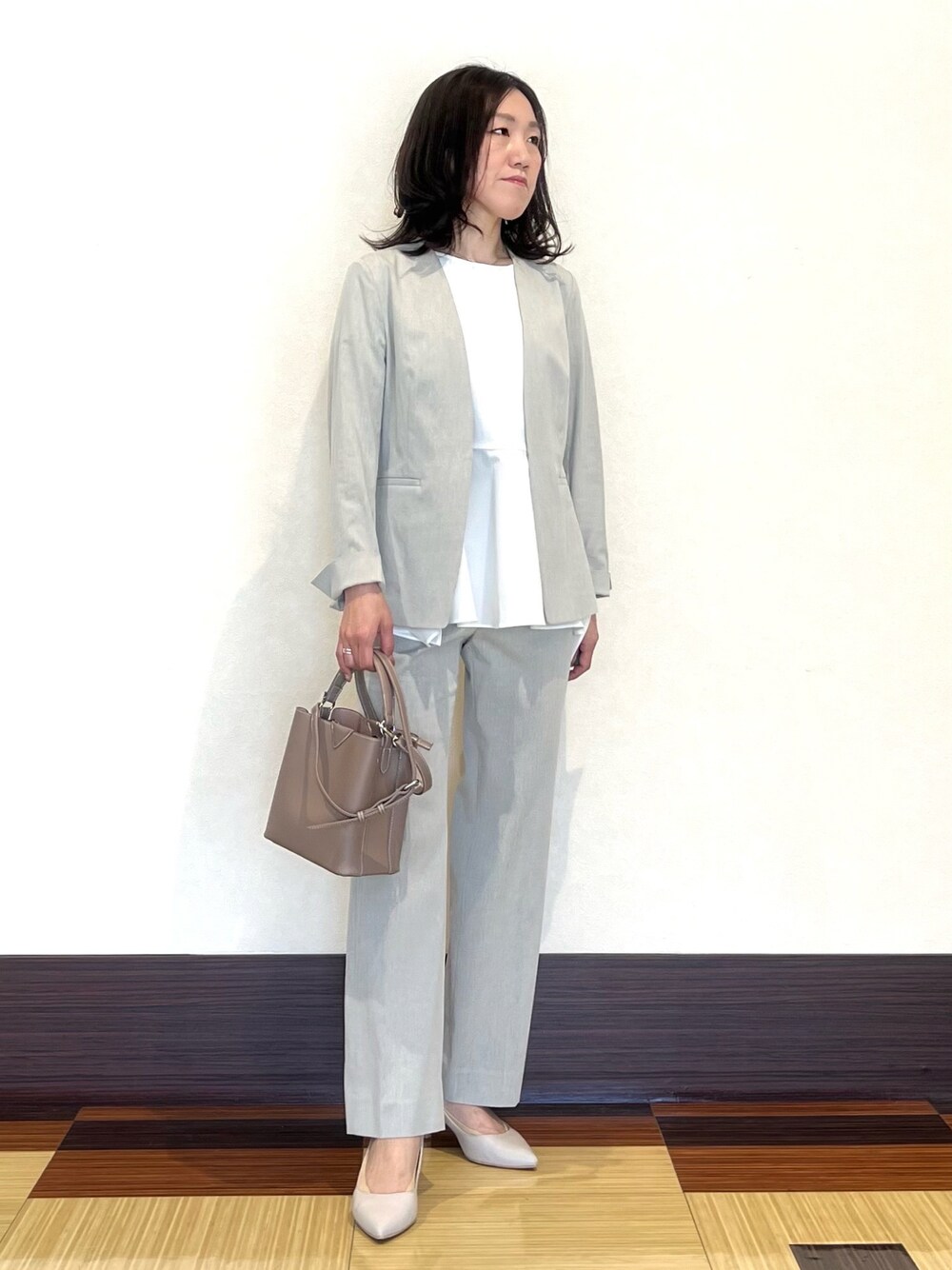 グレー系のスーツジャケット、ホワイト系のシャツ/ブラウス、グレー系のスーツパンツを着用したレディースの春コーディネートの1枚目の写真