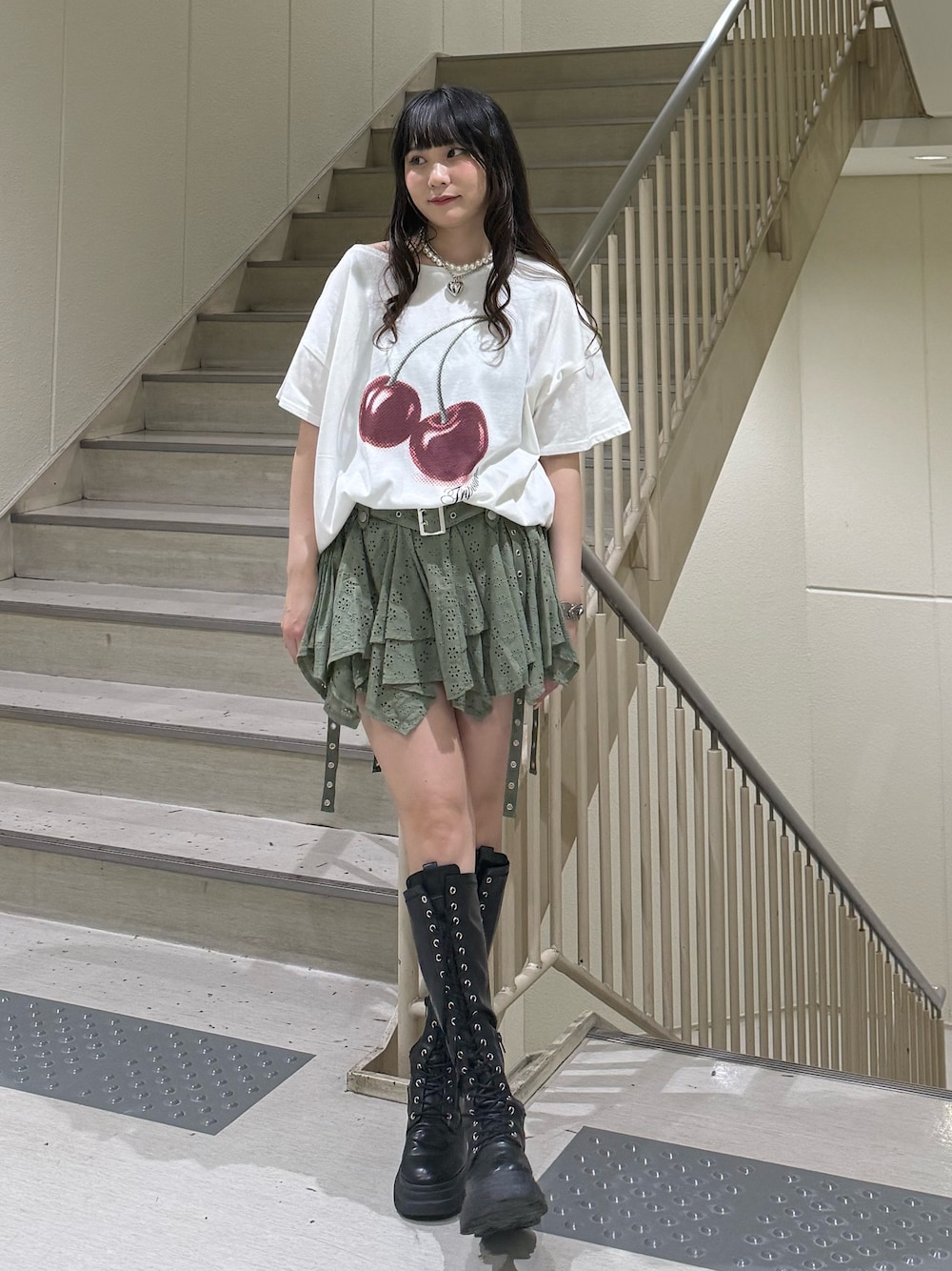 ホワイト系のTシャツ/カットソー、ブラック系のブーツ、グリーン系のスカートを着用したレディースの春コーディネートの1枚目の写真