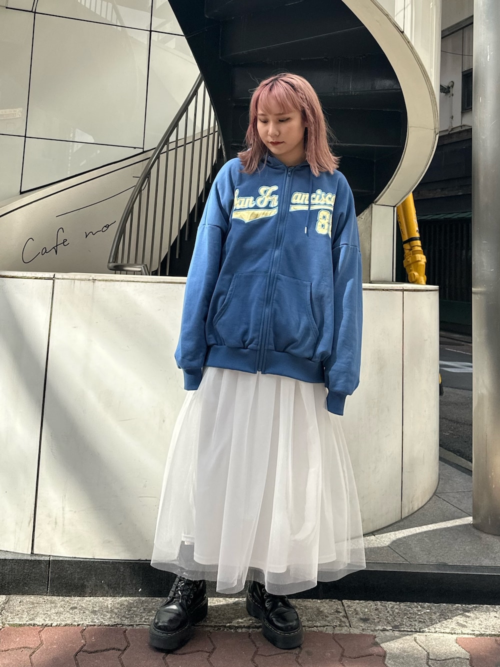 ブルー系のパーカー、ホワイト系のスカート、ブラック系のブーツを着用したレディースの春コーディネートの1枚目の写真