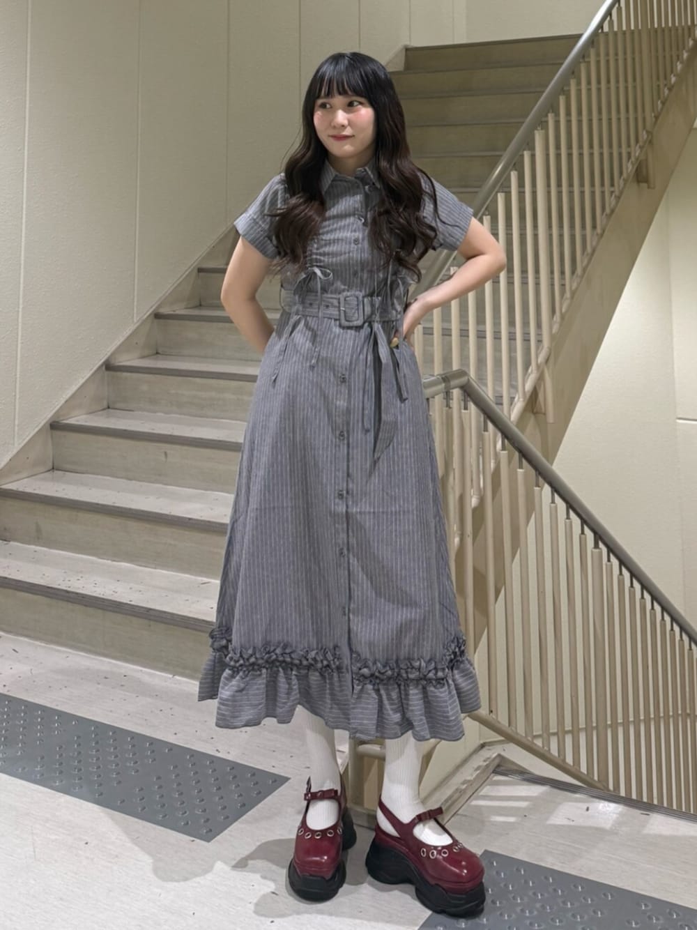 グレー系のワンピース、レッド系のパンプスを着用したレディースの春コーディネートの1枚目の写真