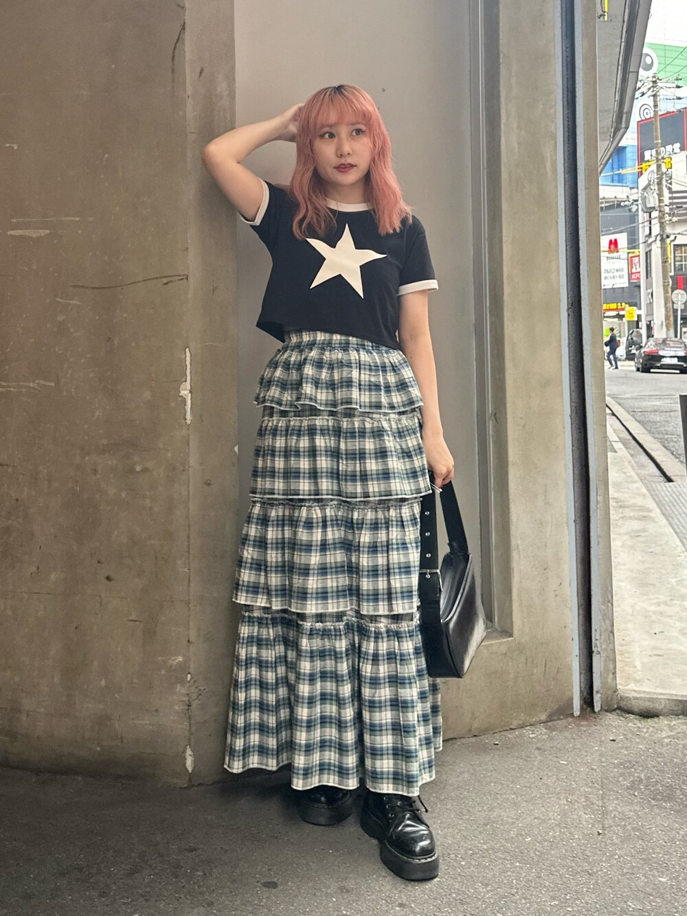 ブラック系のハンドバッグ、ブラック系のTシャツ/カットソー、グリーン系のスカートを着用したレディースの夏コーディネートの1枚目の写真