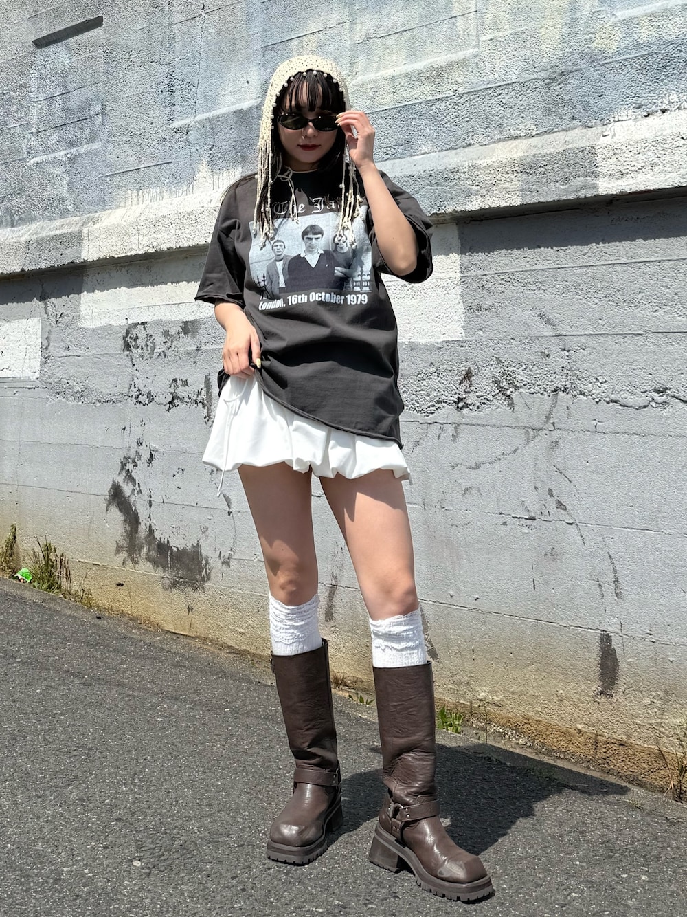 ブラウン系のブーツ、ブラック系のTシャツ/カットソー、ホワイト系のスカートを着用したレディースの春コーディネートの1枚目の写真