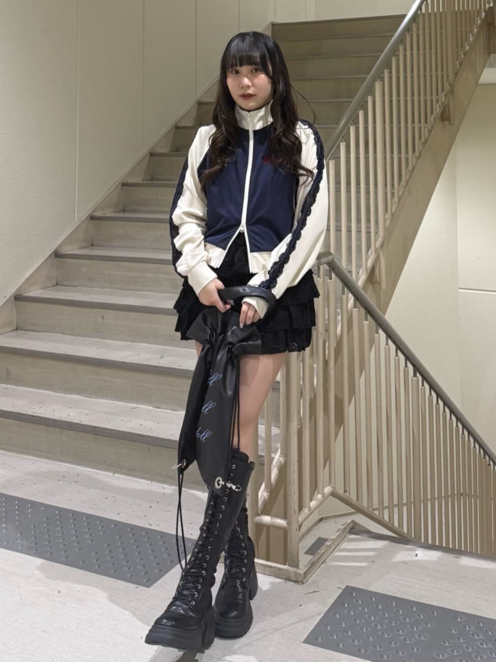 ブラック系のブーツ、ブルー系のジャージ、ブラック系のスカートを着用したレディースの春コーディネートの1枚目の写真