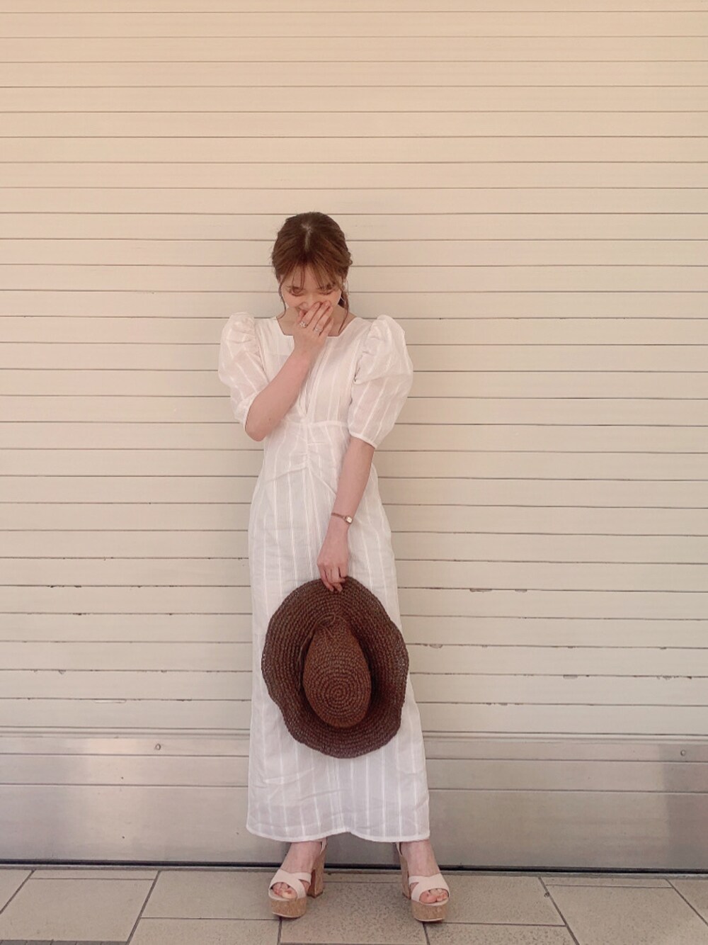 ホワイト系のワンピース、ベージュ系のサンダル、ブラウン系のハットを着用したレディースの春コーディネートの1枚目の写真