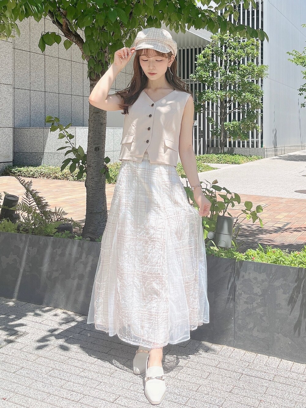 ベージュ系のベスト、ベージュ系のスカート、ホワイト系のローファーを着用したレディースの夏コーディネートの1枚目の写真