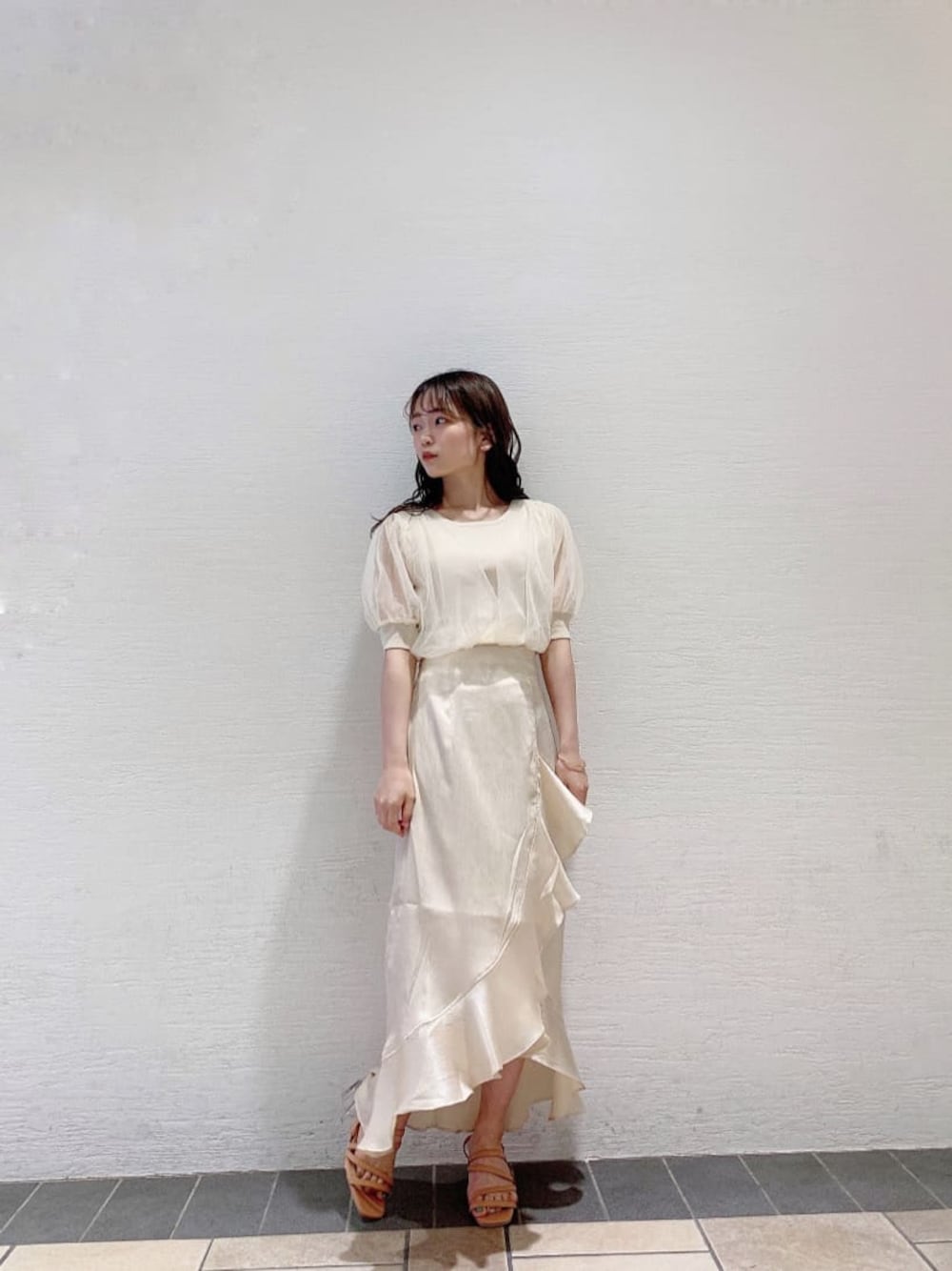 ホワイト系のスカート、ホワイト系のニット/セーター、オレンジ系のサンダルを着用したレディースの夏コーディネートの1枚目の写真