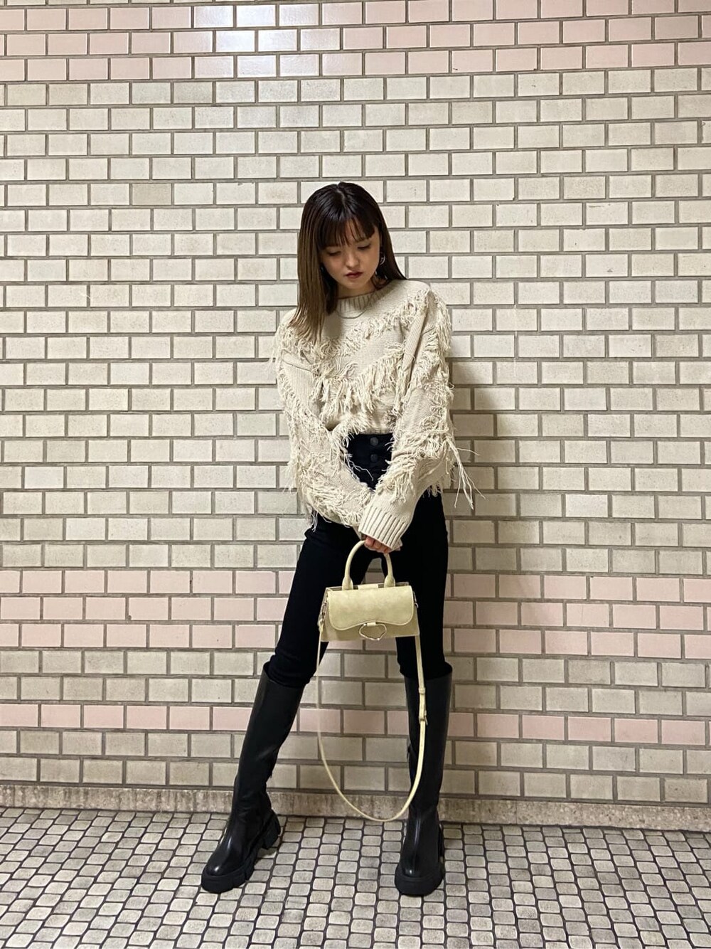 ブラック系のデニムパンツ、ホワイト系のハンドバッグ、ブラック系のブーツを着用したレディースの冬コーディネートの1枚目の写真