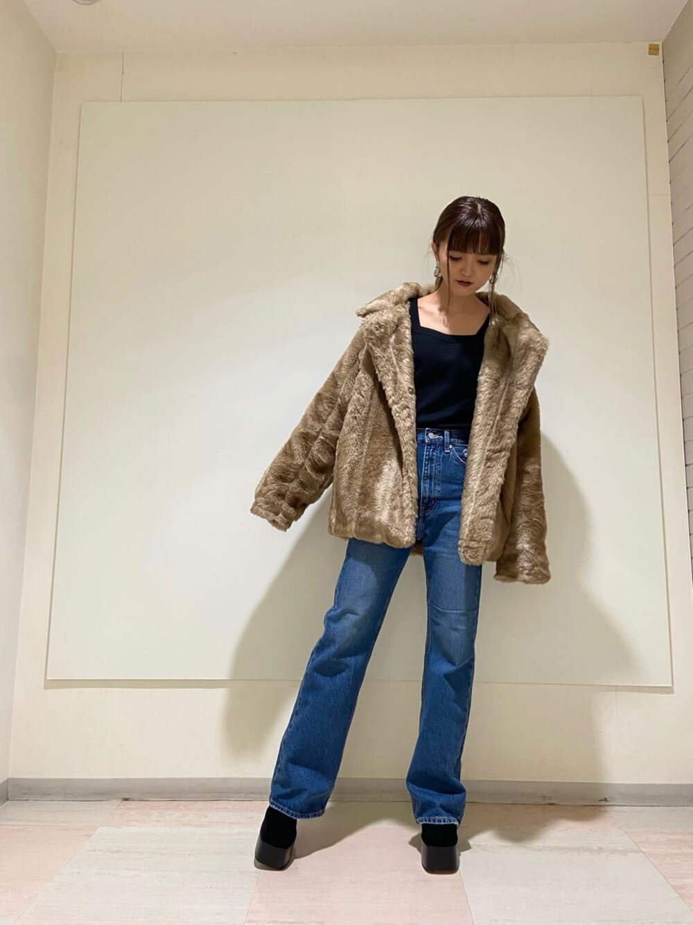 ブルー系のデニムパンツ、ブラック系のブーツ、ベージュ系のその他アウターを着用したレディースの冬コーディネートの1枚目の写真