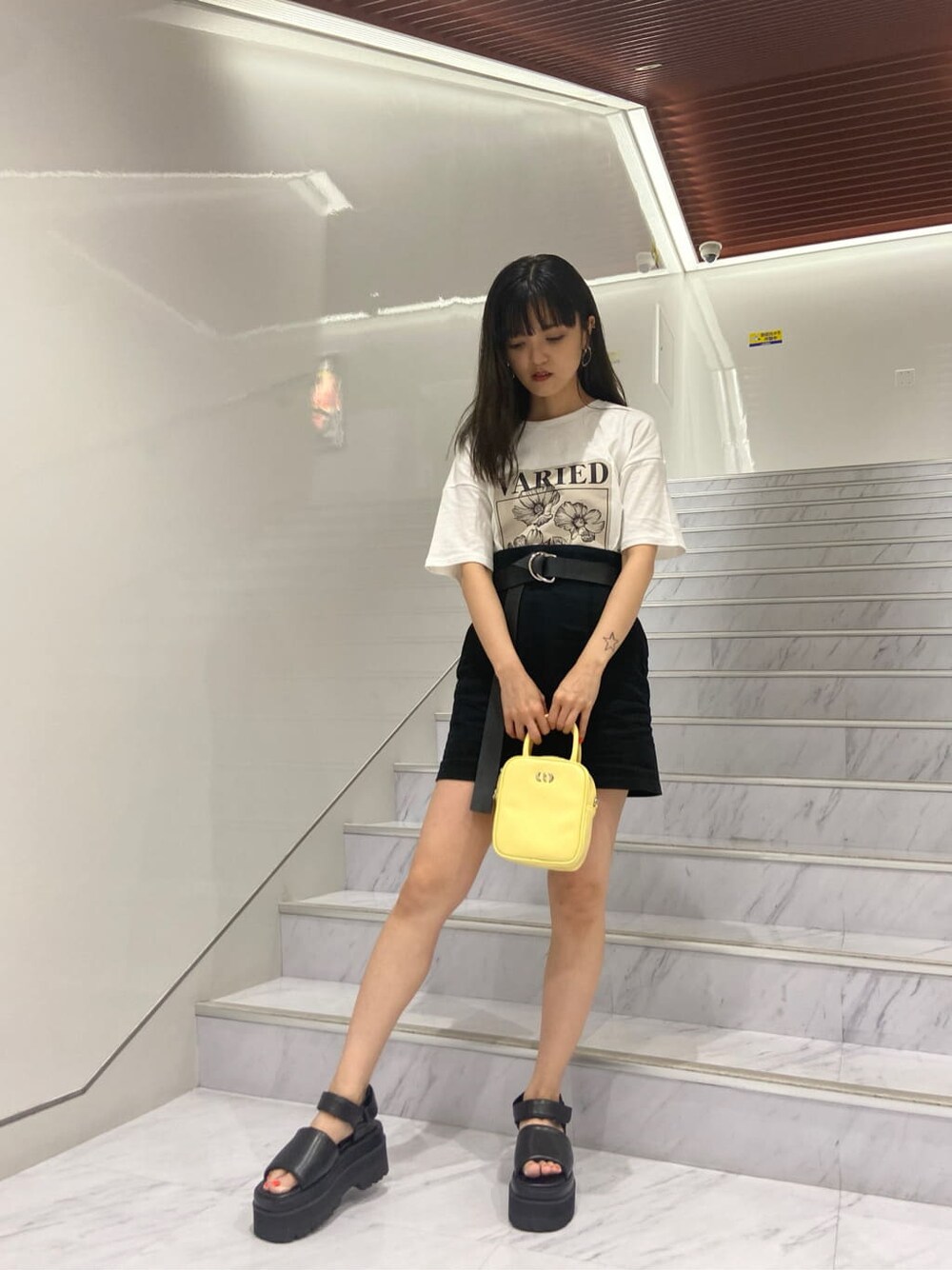 ブラック系のサンダル、ホワイト系のTシャツ/カットソー、ブラック系のスカートを着用したレディースの夏コーディネートの1枚目の写真