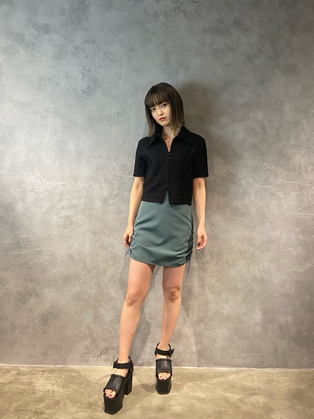 ブラック系のシャツ/ブラウス、グリーン系のスカート、ブラック系のサンダルを着用したレディースの春コーディネートの1枚目の写真