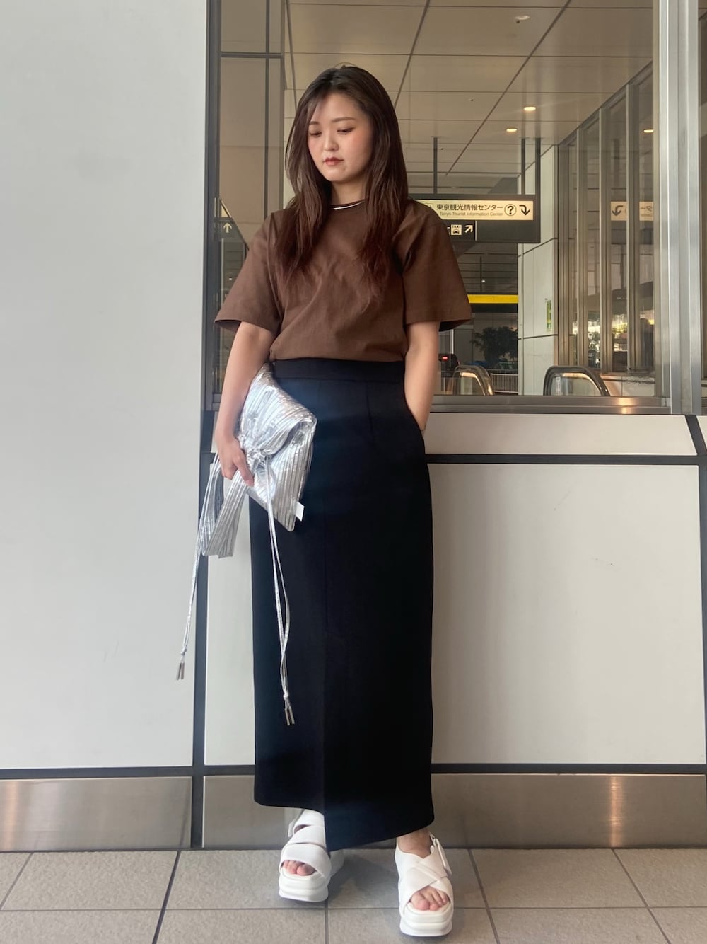 ブラック系のスカート、ブラウン系のTシャツ/カットソー、ホワイト系のサンダルを着用したレディースの春コーディネートの1枚目の写真