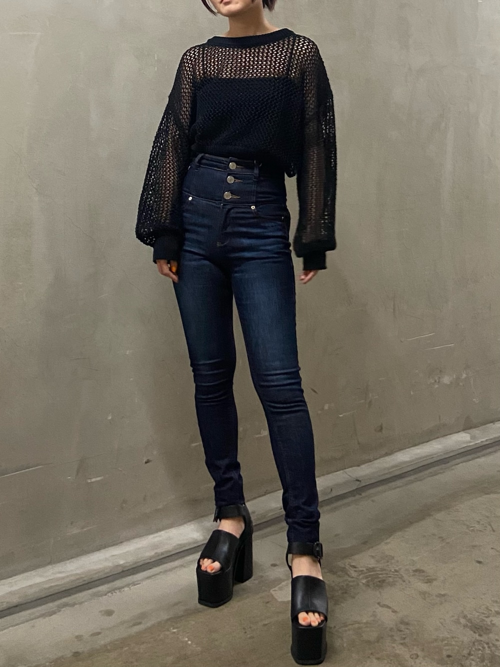 ブラック系のニット/セーター、ブルー系のデニムパンツ、ブラック系のサンダルを着用したレディースの春コーディネートの1枚目の写真