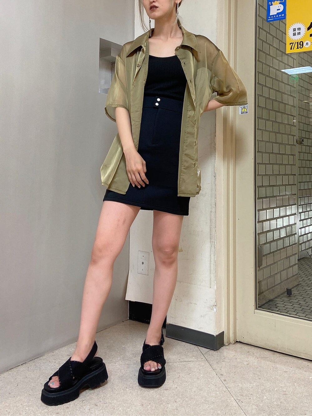 イエロー系のシャツ/ブラウス、ブラック系のスカート、ブラック系のサンダルを着用したレディースの夏コーディネートの1枚目の写真