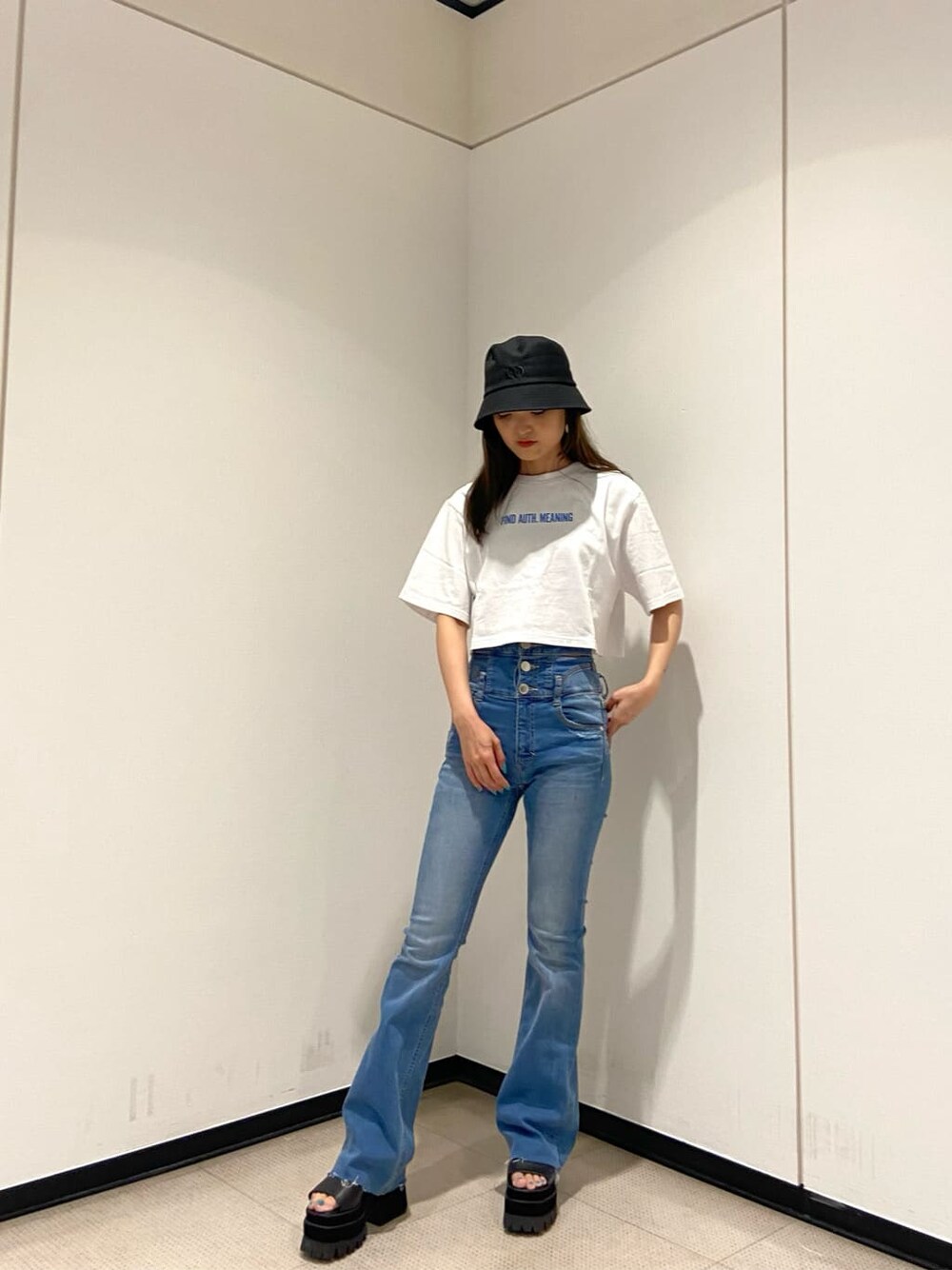 ブルー系のデニムパンツ、ブラック系のサンダル、ホワイト系のTシャツ/カットソーを着用したレディースの夏コーディネートの1枚目の写真