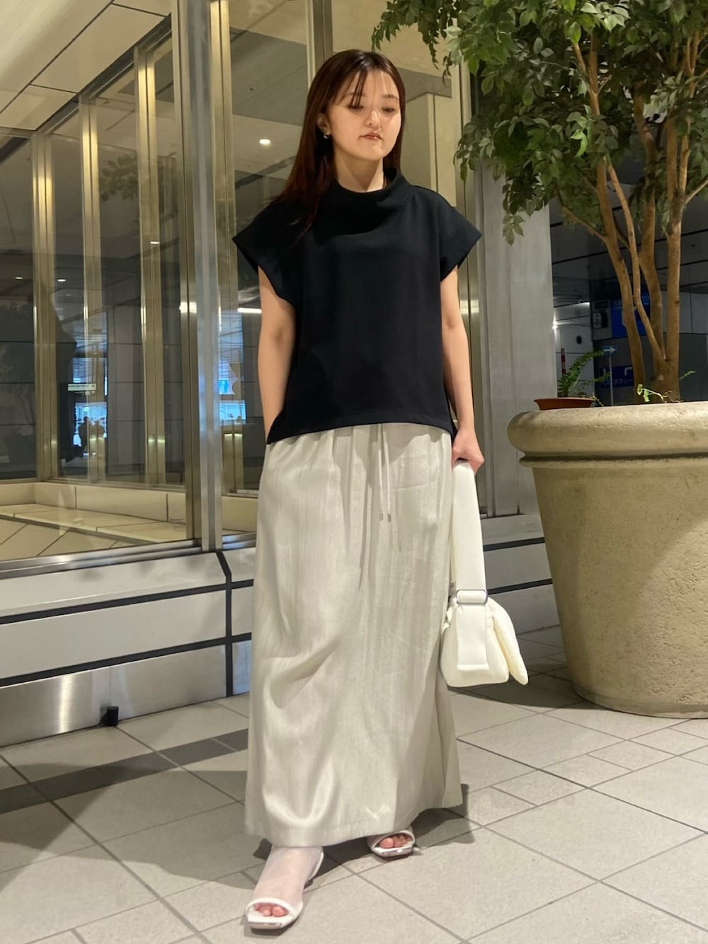 ブラック系のTシャツ/カットソー、ベージュ系のスカート、ホワイト系のサンダルを着用したレディースの春コーディネートの1枚目の写真