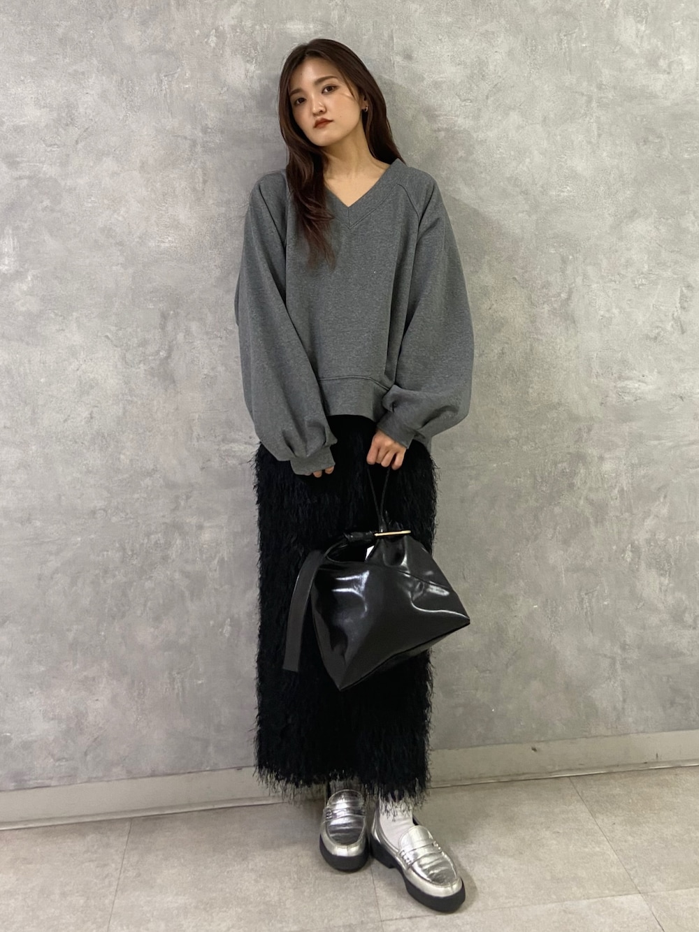 グレー系のTシャツ/カットソー、ブラック系のスカート、シルバー系のローファーを着用したレディースの冬コーディネートの1枚目の写真