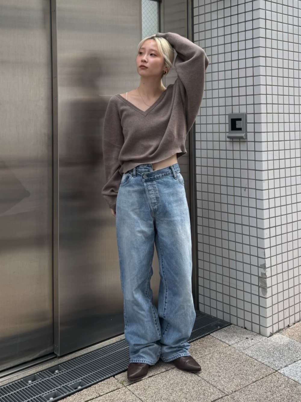 ブラウン系のブーツ、ブルー系のデニムパンツ、ベージュ系のニット/セーターを着用したレディースの秋コーディネートの1枚目の写真