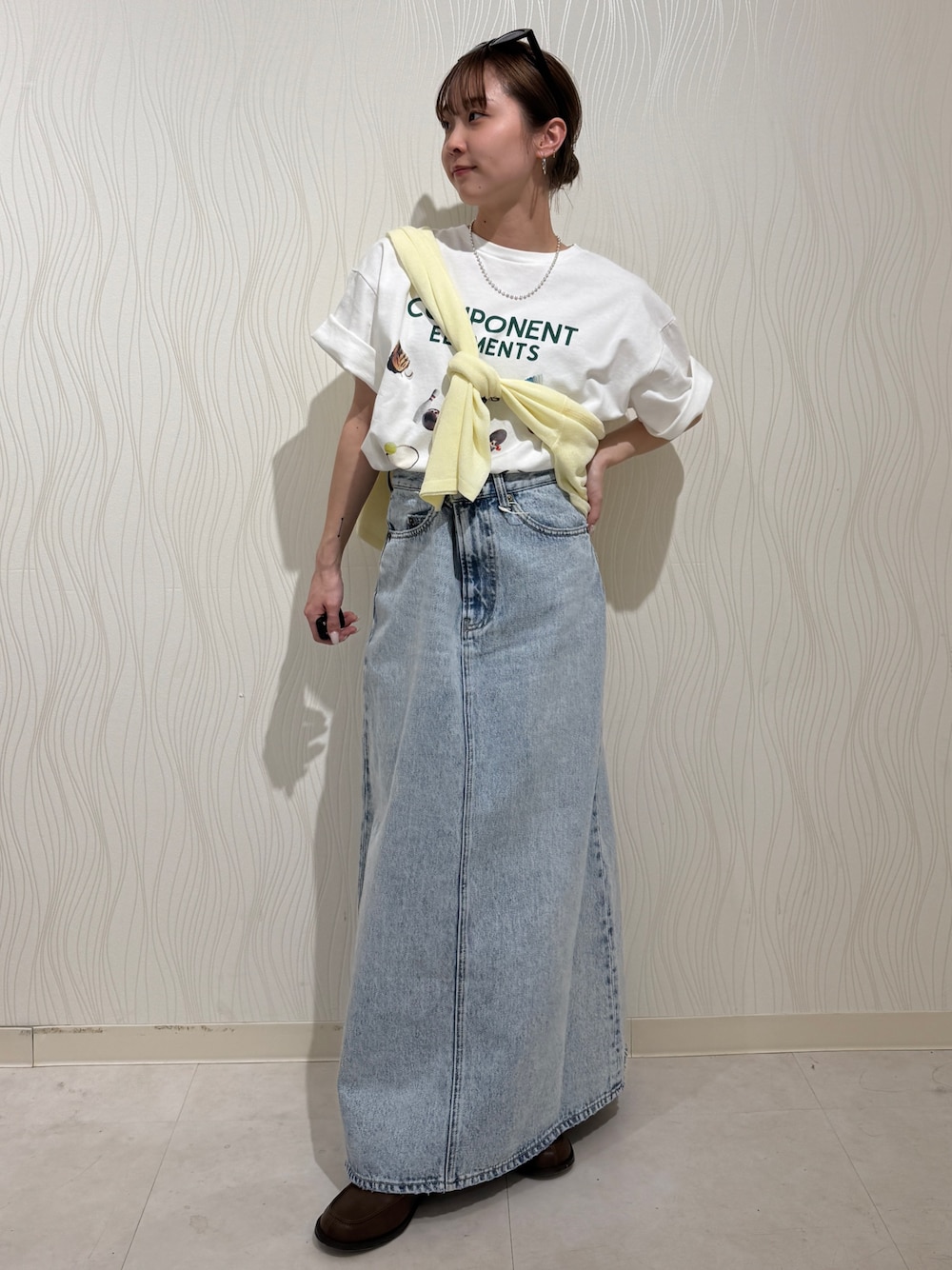 ホワイト系のTシャツ/カットソー、イエロー系のニット/セーター、ブルー系のスカートを着用したレディースの春コーディネートの1枚目の写真