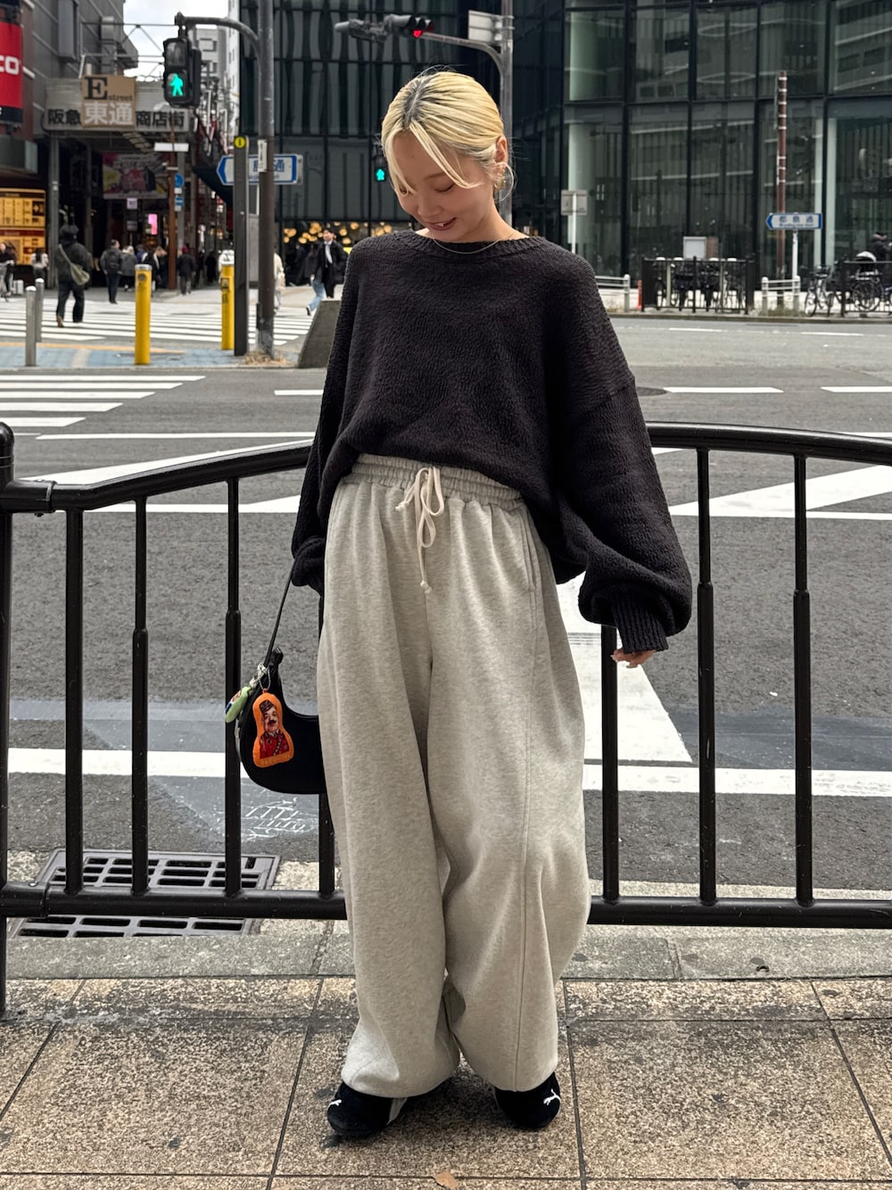 グレー系のニット/セーター、ホワイト系のスウェットパンツ、ブラック系のスニーカーを着用したレディースの冬コーディネートの1枚目の写真