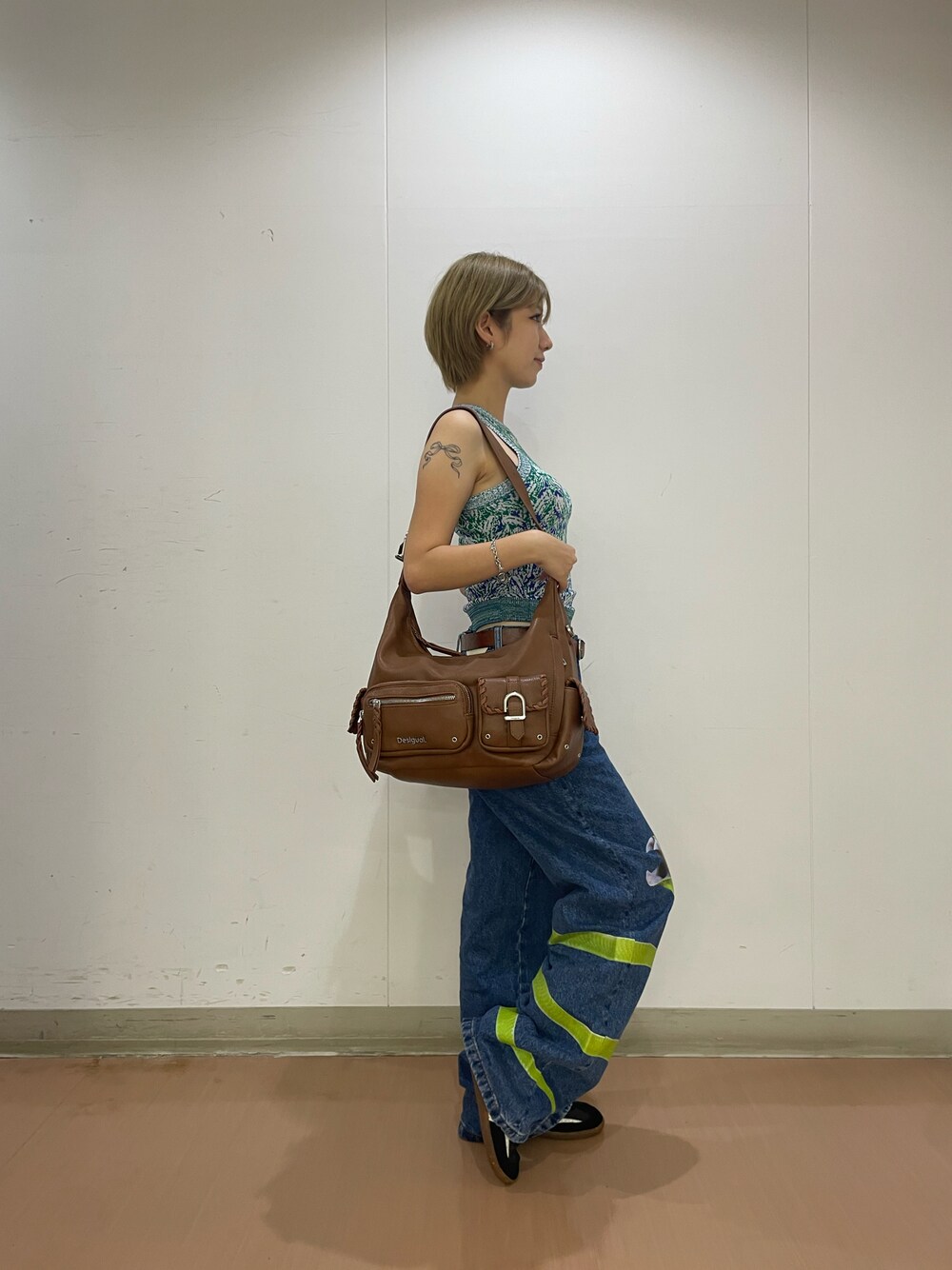 ブルー系のデニムパンツ、グリーン系のタンクトップ、ブラウン系のショルダーバッグを着用したレディースの夏コーディネートの1枚目の写真