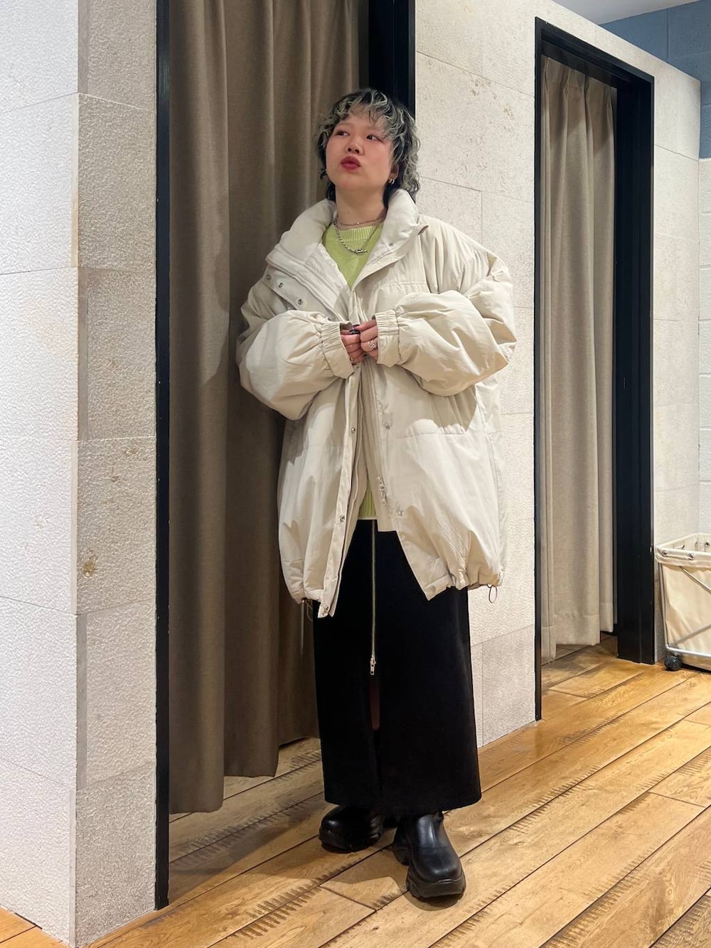 ブラック系のブーツ、ホワイト系のブルゾン、グリーン系のニット/セーターを着用したレディースの冬コーディネートの1枚目の写真