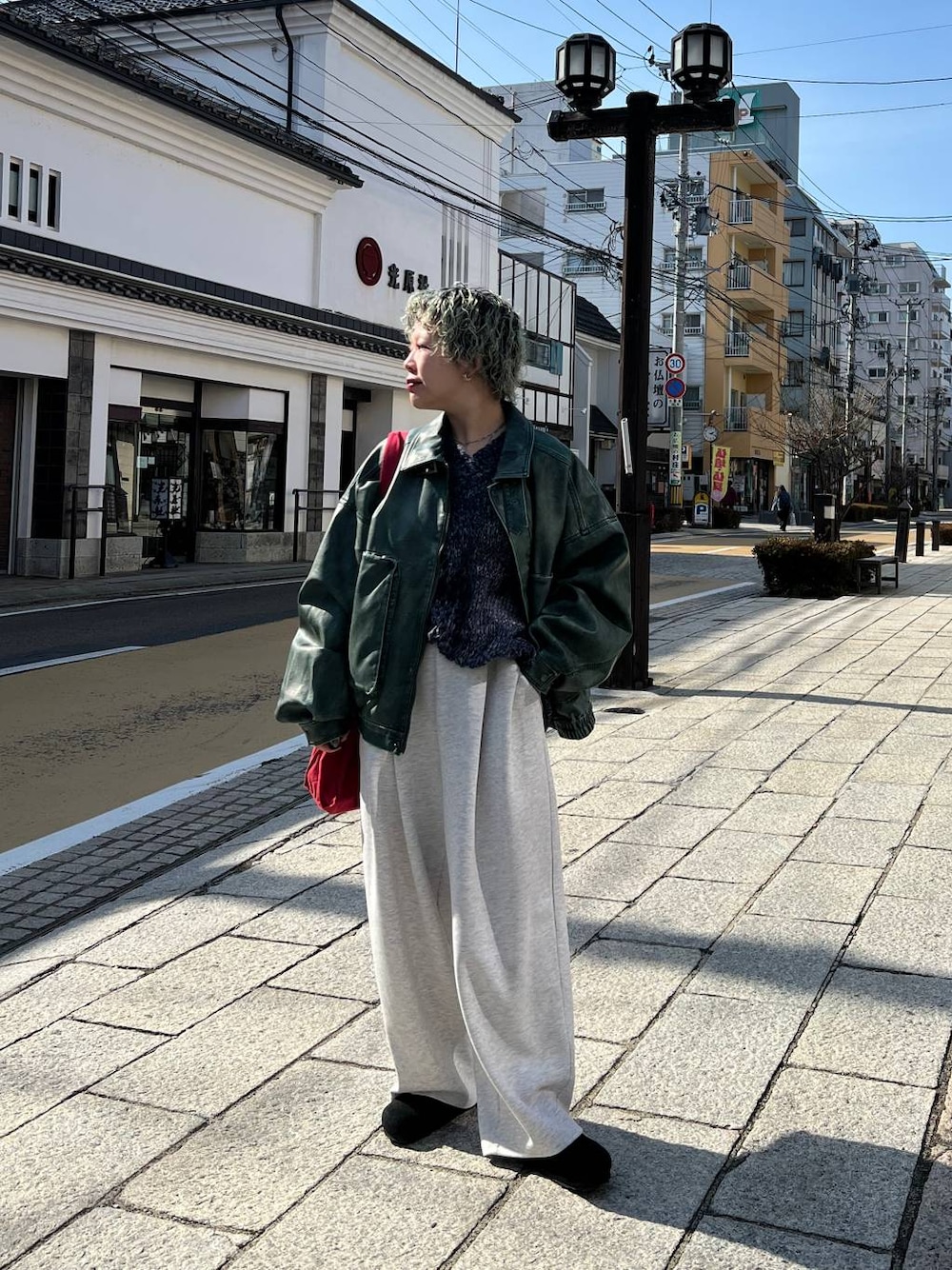 グレー系のスウェットパンツ、グリーン系のブルゾン、シルバー系のネックレスを着用したレディースの春コーディネートの1枚目の写真