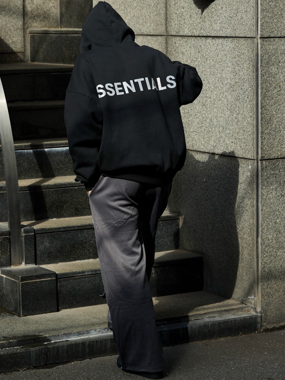 ブラック系のパーカー、グレー系のチノパンツを着用したメンズの秋コーディネートの1枚目の写真