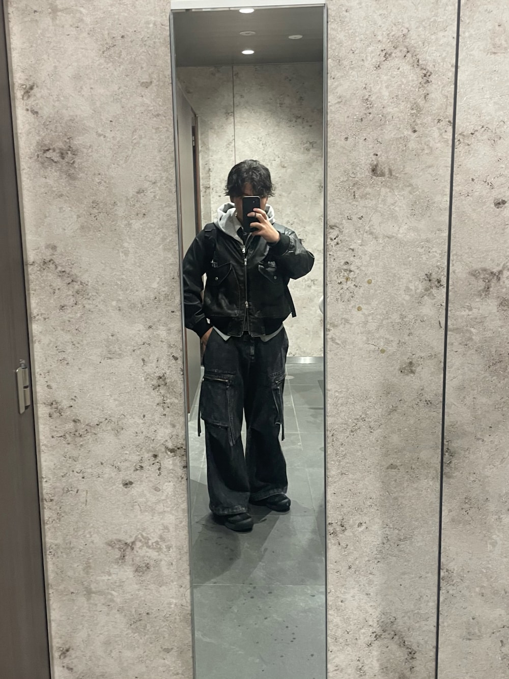 ブラック系のブルゾン、ブラック系のカーゴパンツ、グレー系のパーカーを着用したメンズの秋コーディネートの1枚目の写真