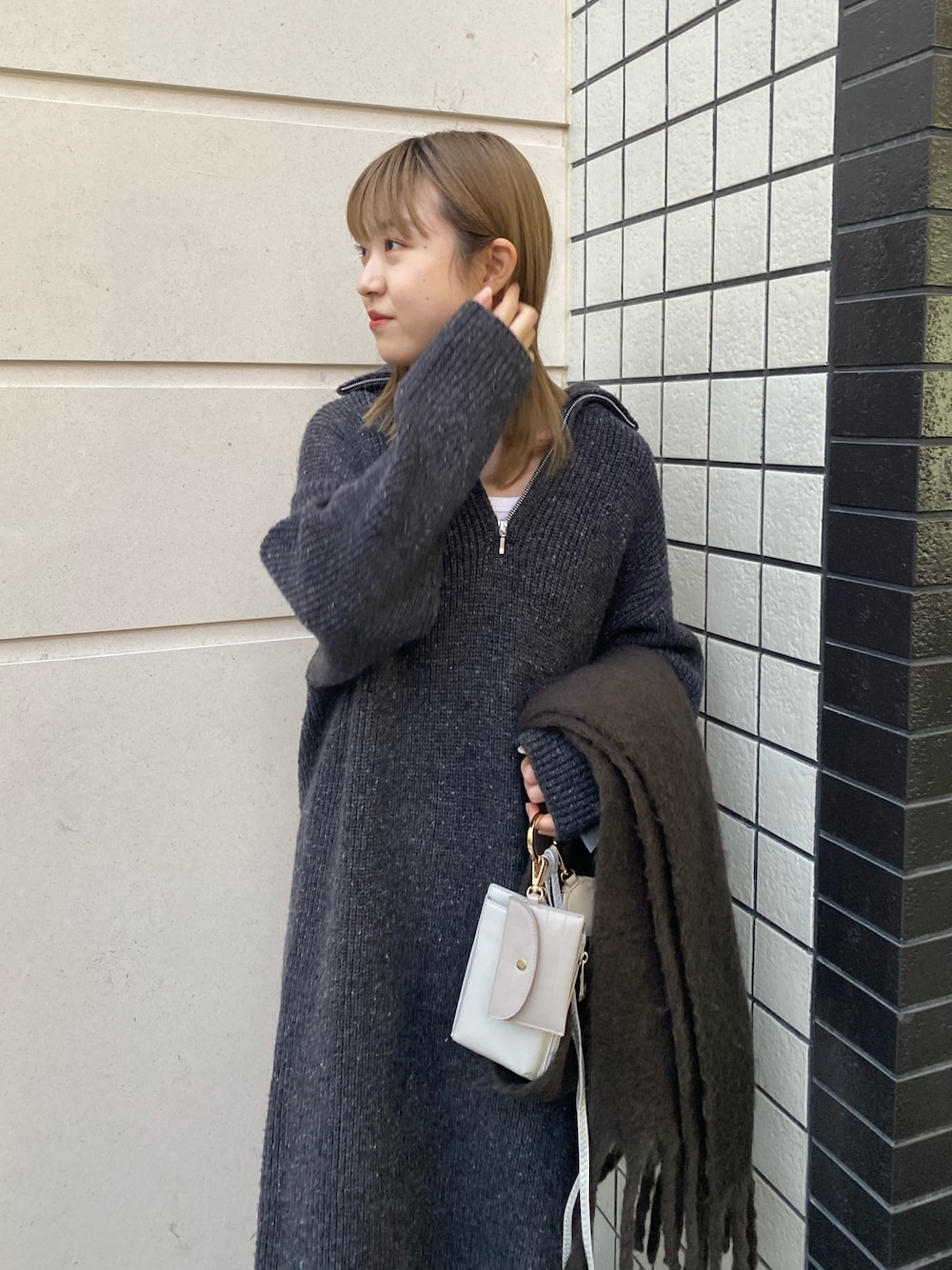 グレー系のワンピース、ホワイト系のトートバッグ、ブラック系のブーツを着用したレディースの冬コーディネートの2枚目の写真