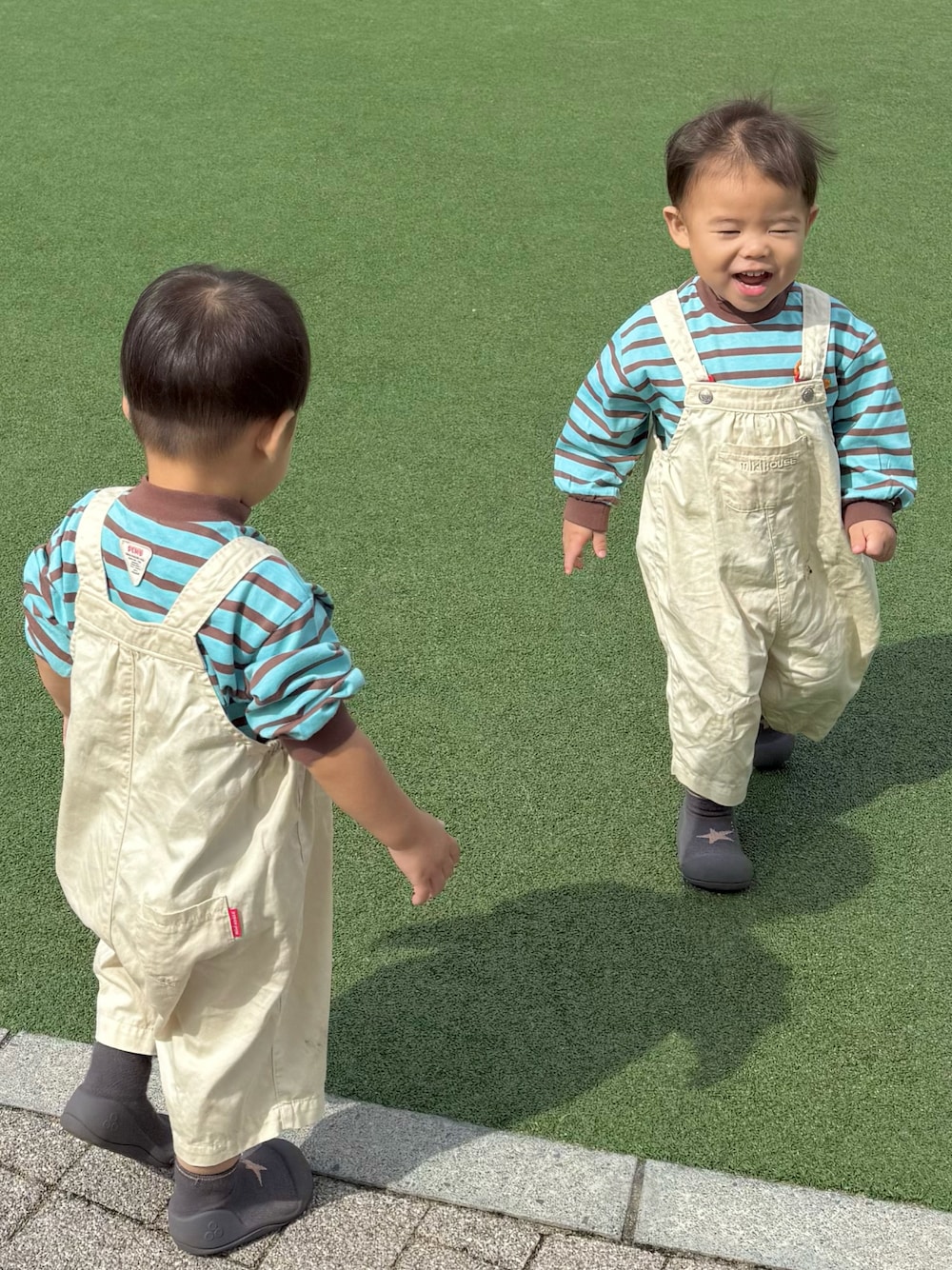 ブルー系のTシャツ/カットソー、ベージュ系のサロペット/オーバーオール、ブラック系のサンダルを着用したキッズの秋コーディネートの1枚目の写真