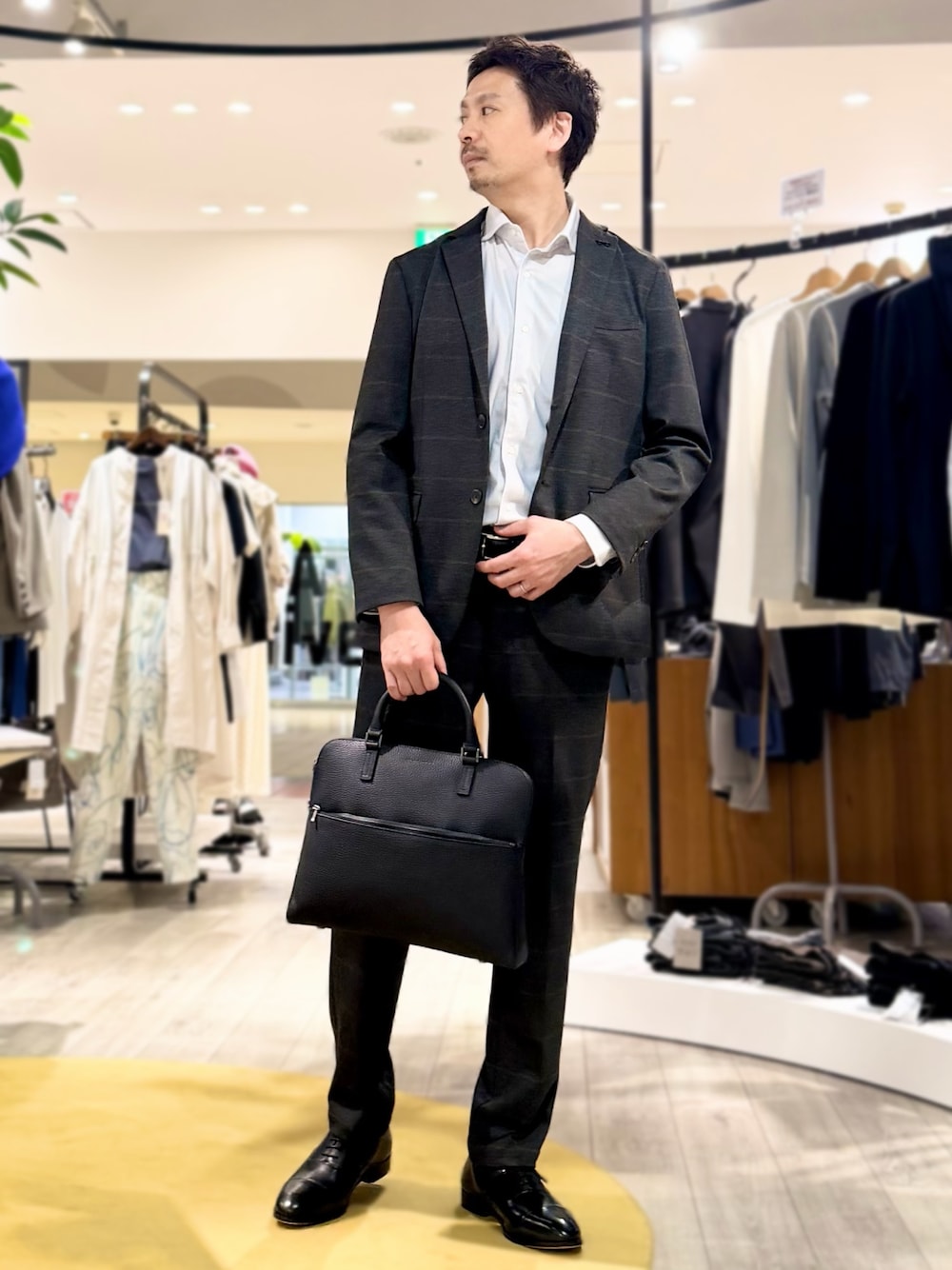 ブラック系のドレスシューズ、ブラック系のビジネスバッグ、ブラック系のベルトを着用したメンズの春コーディネートの1枚目の写真