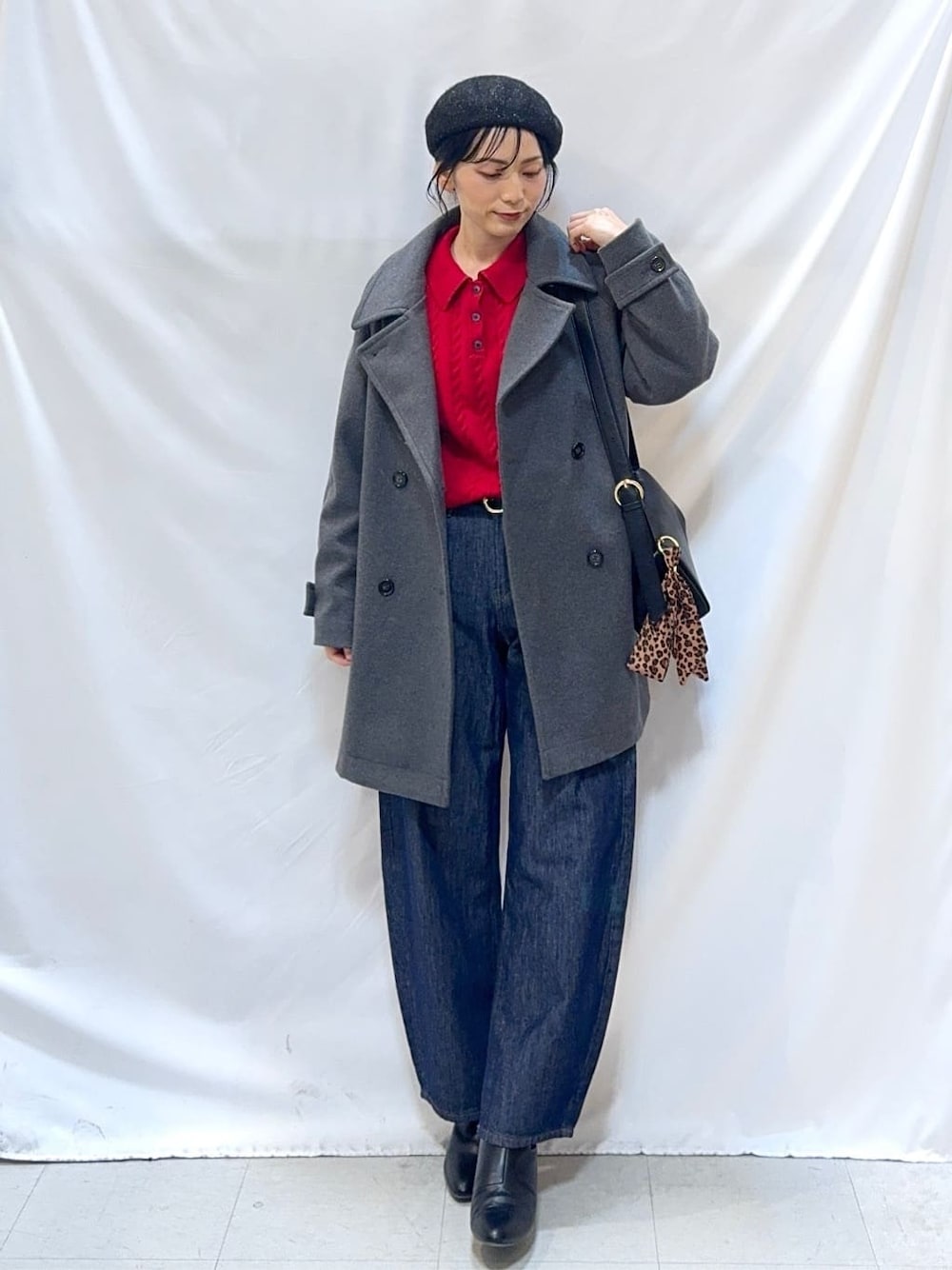 グレー系のチェスターコート、レッド系のニット/セーター、ブルー系のデニムパンツを着用したレディースの冬コーディネートの1枚目の写真