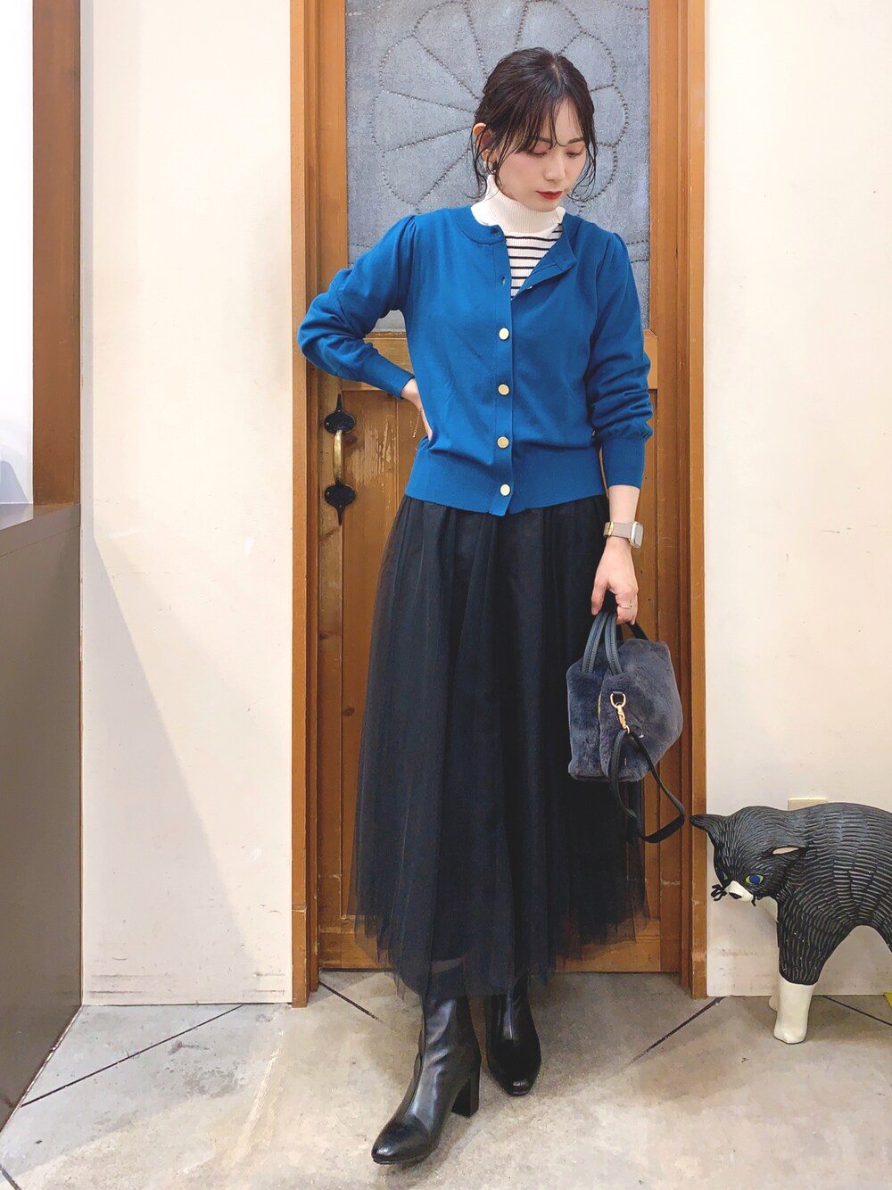 ホワイト系のニット/セーター、ブルー系のカーディガン/ボレロ、ブラック系のスカートを着用したレディースの冬コーディネートの1枚目の写真