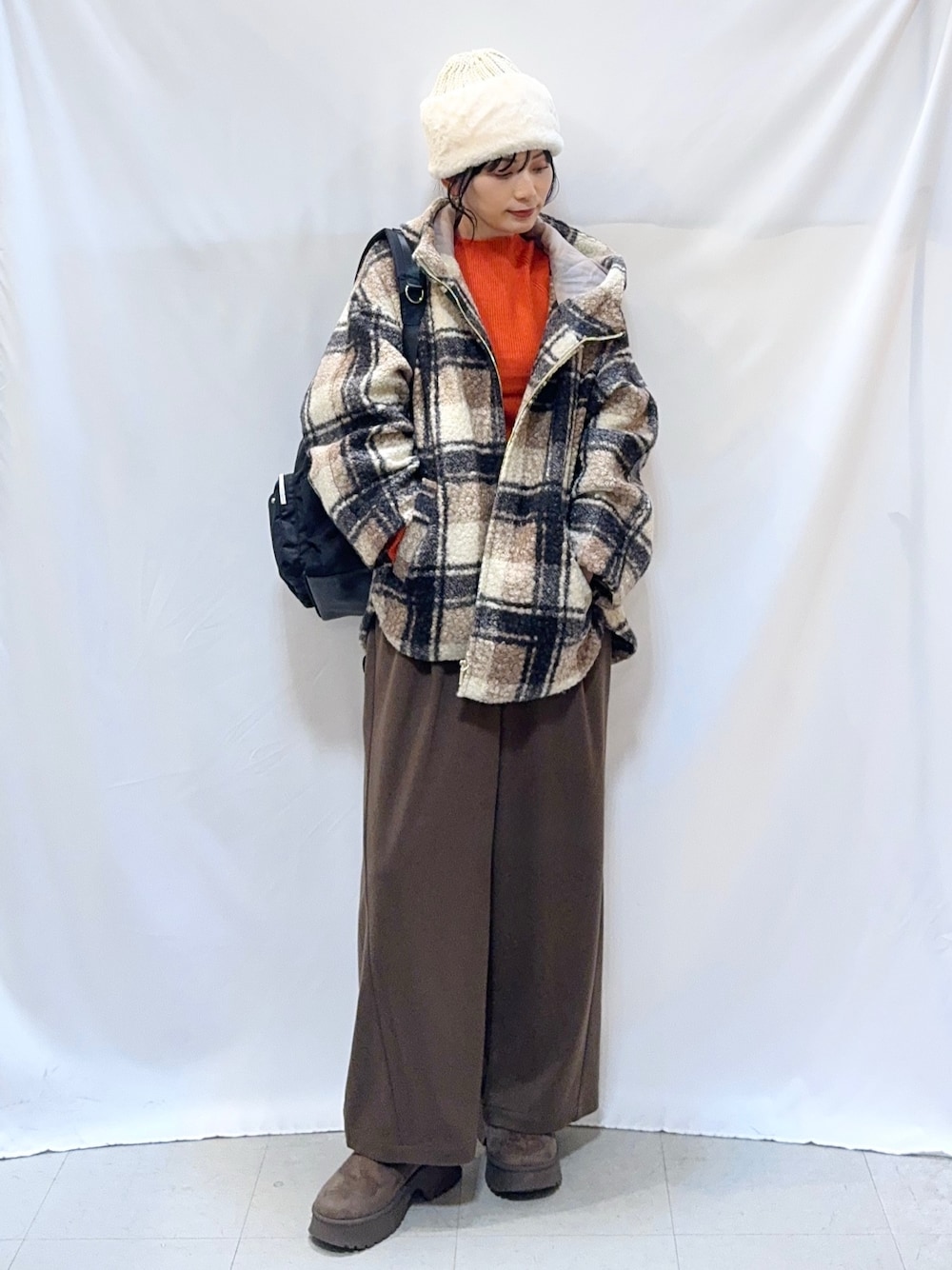 ブラウン系のその他アウター、オレンジ系のニット/セーター、ブラウン系のその他パンツを着用したレディースの秋コーディネートの1枚目の写真