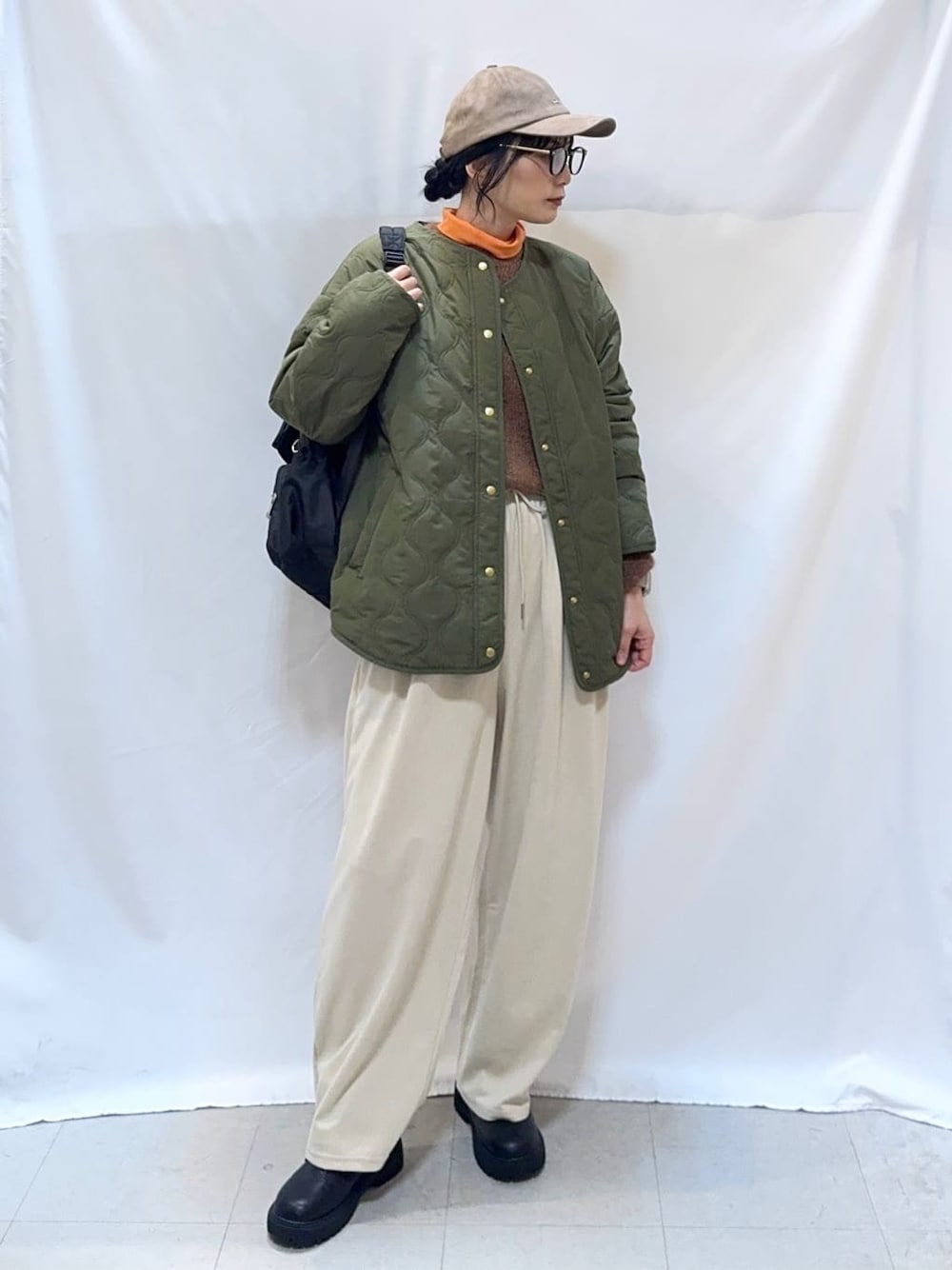 グリーン系のブルゾン、ブラウン系のニット/セーター、オレンジ系のTシャツ/カットソーを着用したレディースの秋コーディネートの1枚目の写真