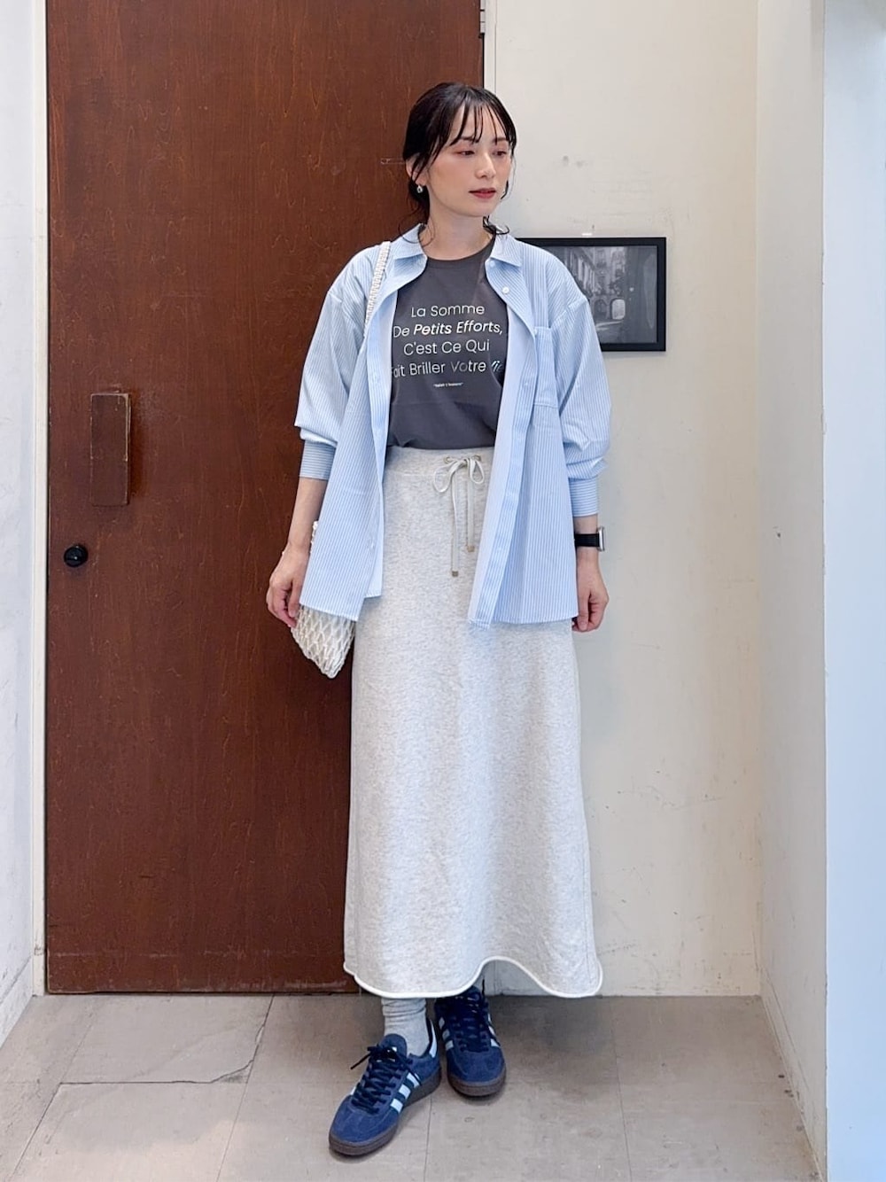 ブルー系のシャツ/ブラウス、グレー系のスカート、ホワイト系のショルダーバッグを着用したレディースの春コーディネートの1枚目の写真