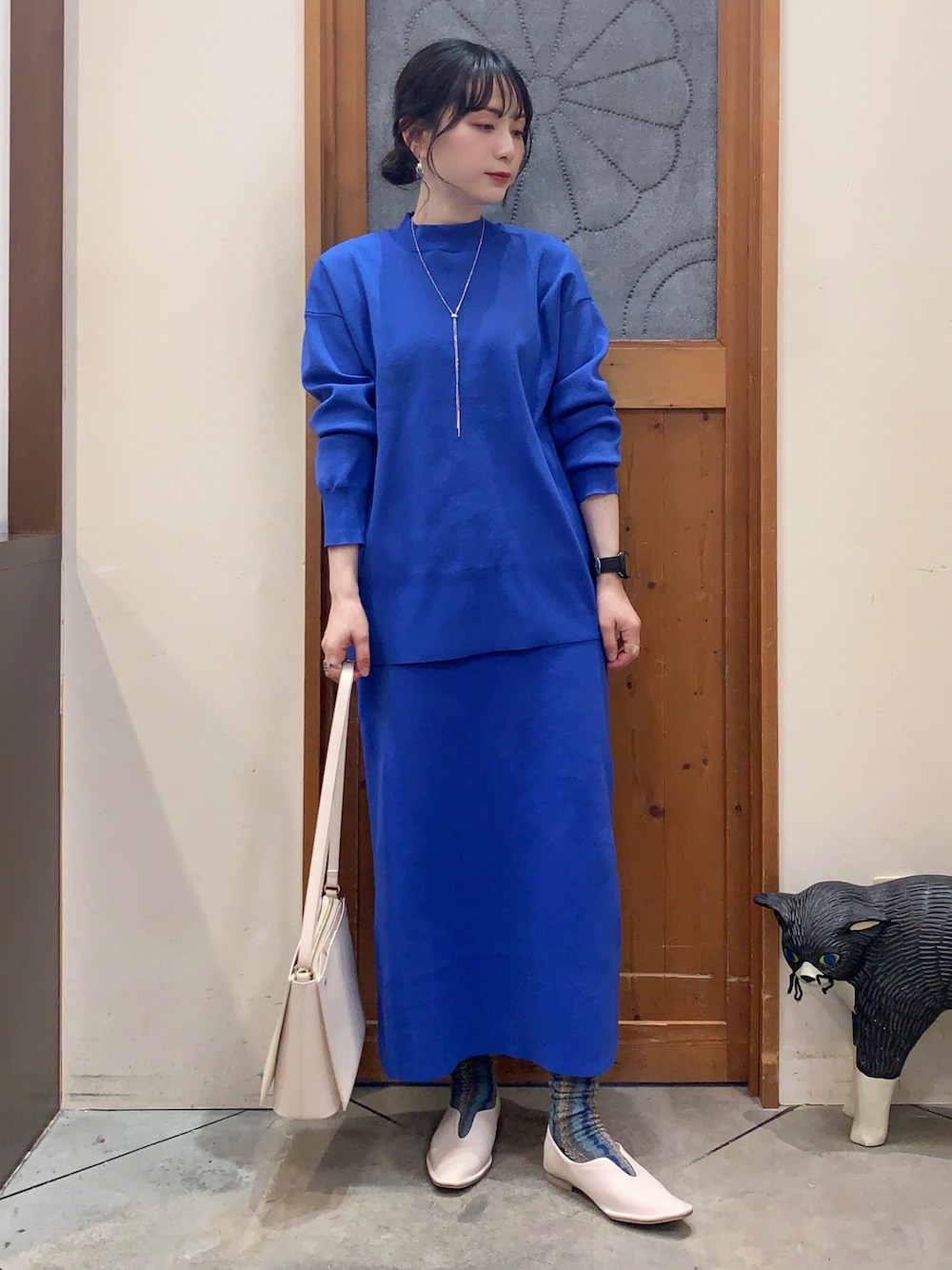 ブルー系のニット/セーター、ブルー系のスカート、ホワイト系のパンプスを着用したレディースの冬コーディネートの1枚目の写真